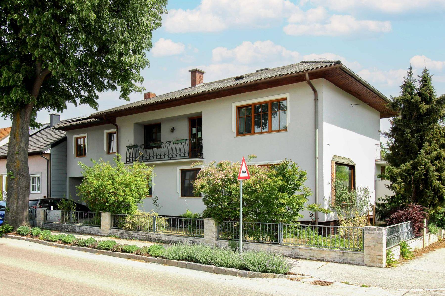 Gepflegtes Einfamilienhaus mit Satteldach, kleinem Balkon und Vorgarten an einer ruhigen Straße.