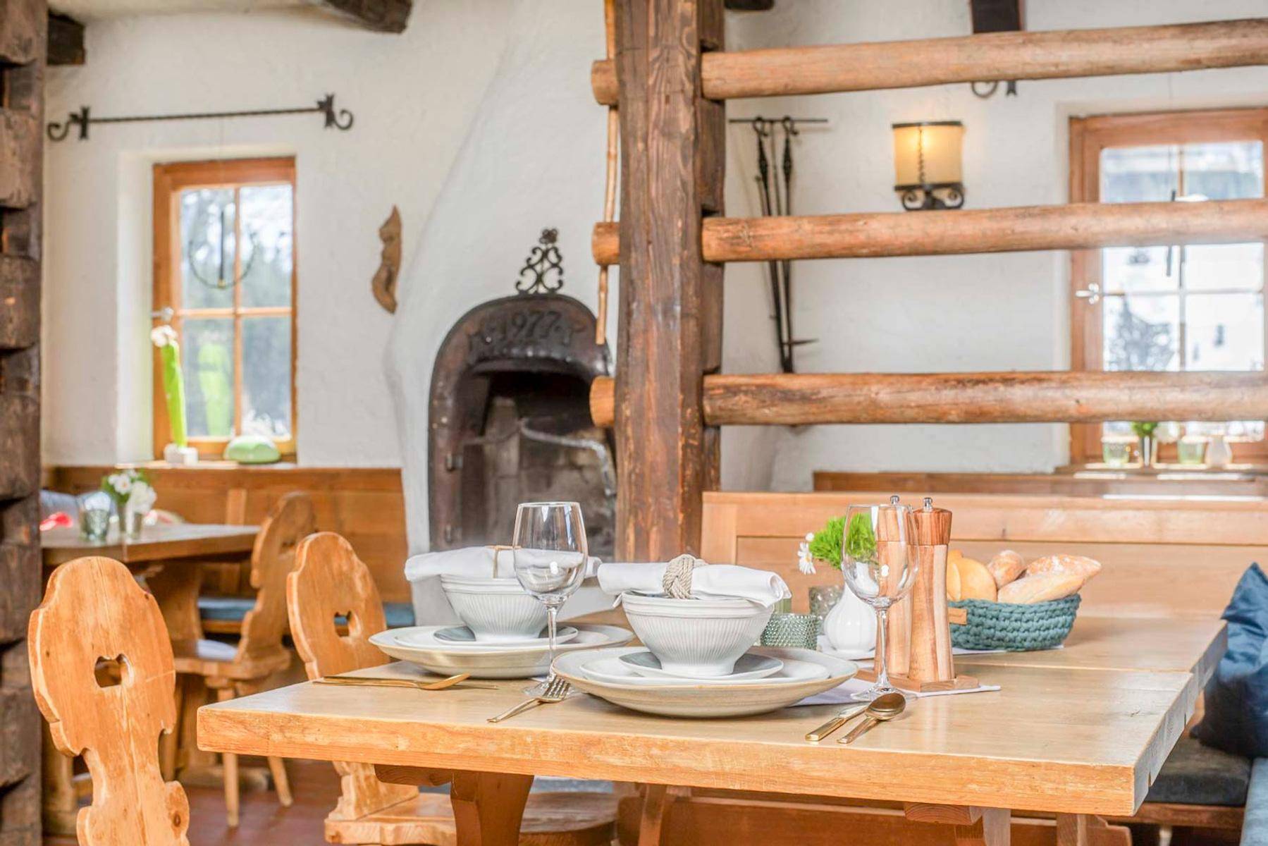 Rustikaler Essbereich mit Holztischen und -stühlen, traditionellem Ofen und gemütlicher Atmosphäre.