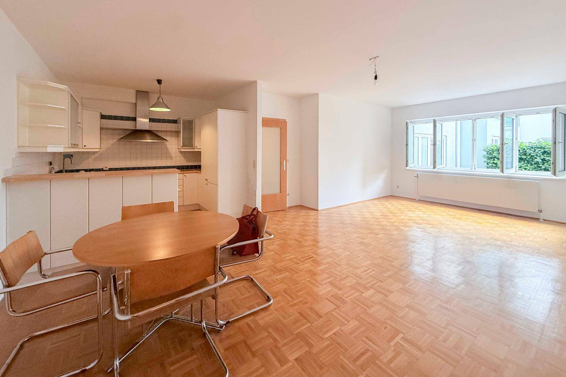 Offener Wohn- und Essbereich mit integrierter Küche und Parkettboden, ideal für geselliges Beisammensein.