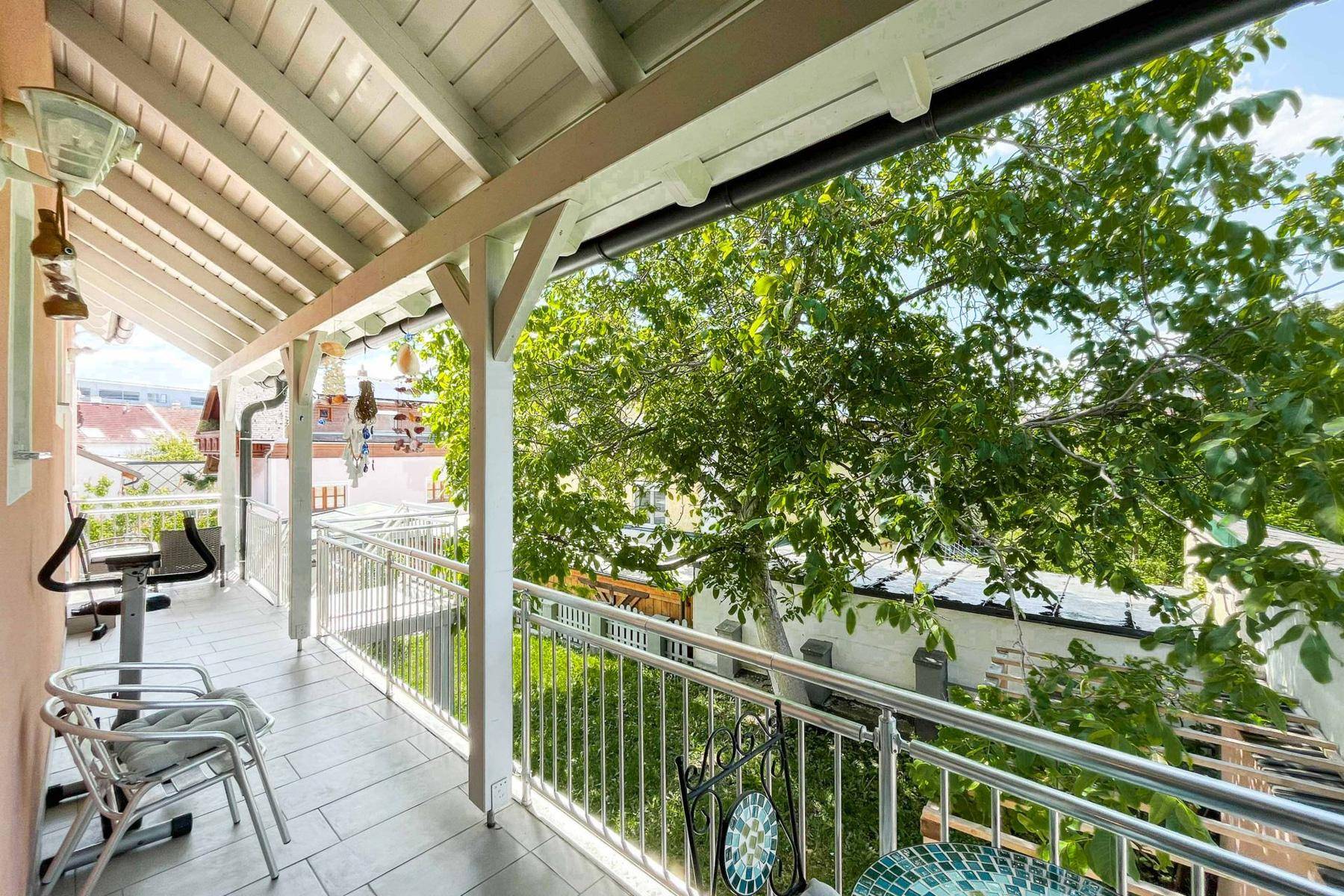 Überdachter Balkon mit Sitzgelegenheiten und Blick ins Grüne, ideal zum Entspannen im Freien.