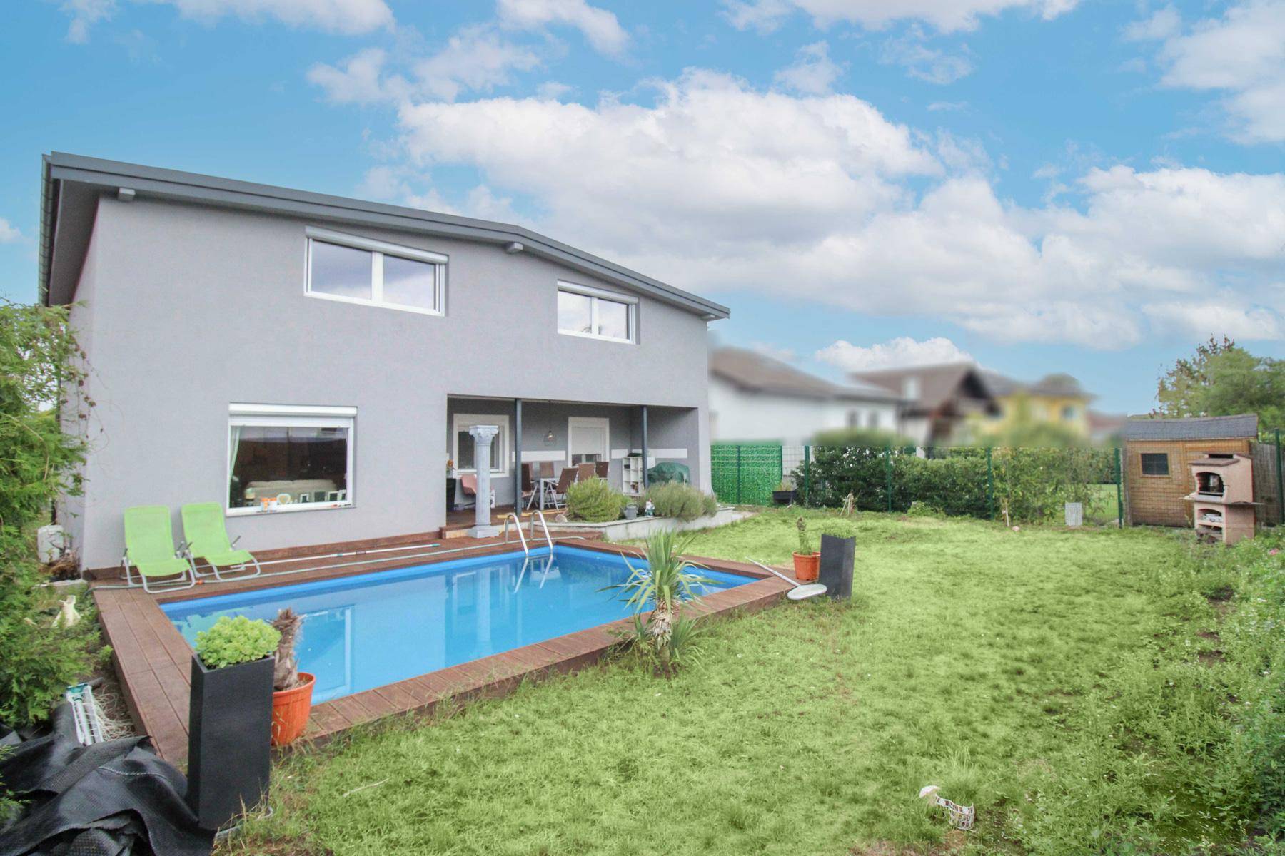 Hinterhof mit Swimmingpool, Holzdeck und weitläufiger Rasenfläche hinter dem Haus.