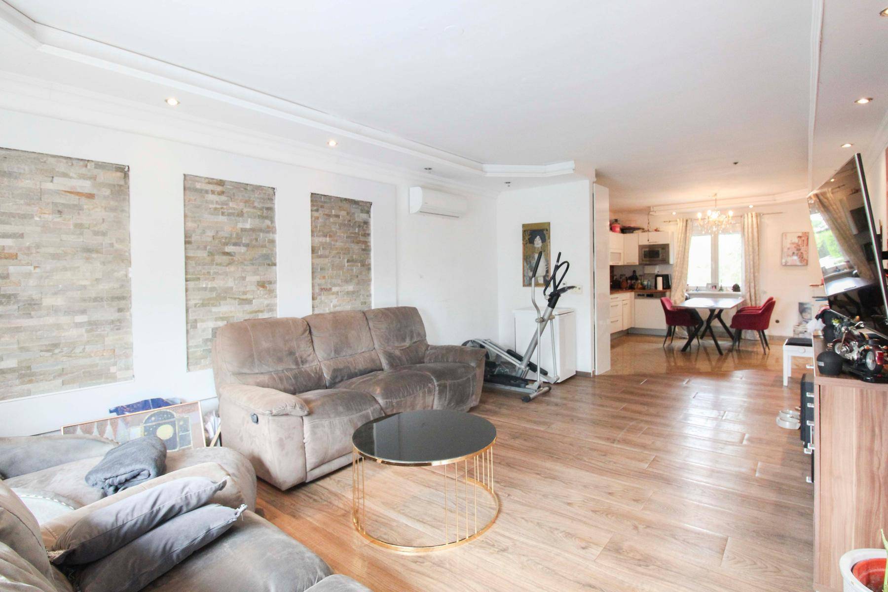 Geräumiges Wohnzimmer mit Holzboden, bequemen Sofas und dekorativen Steinwänden.