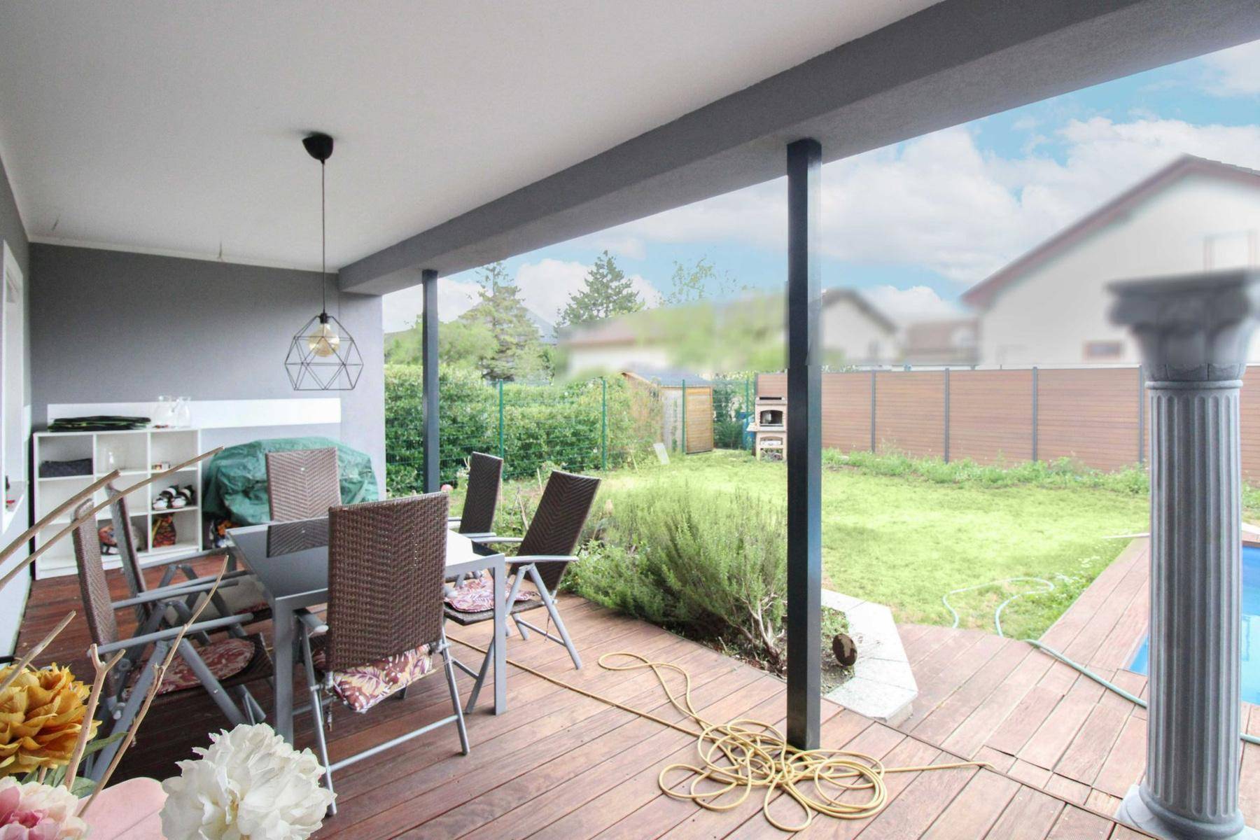 Überdachte Terrasse mit Gartenmöbeln, Holzdeck und Blick auf den Garten.