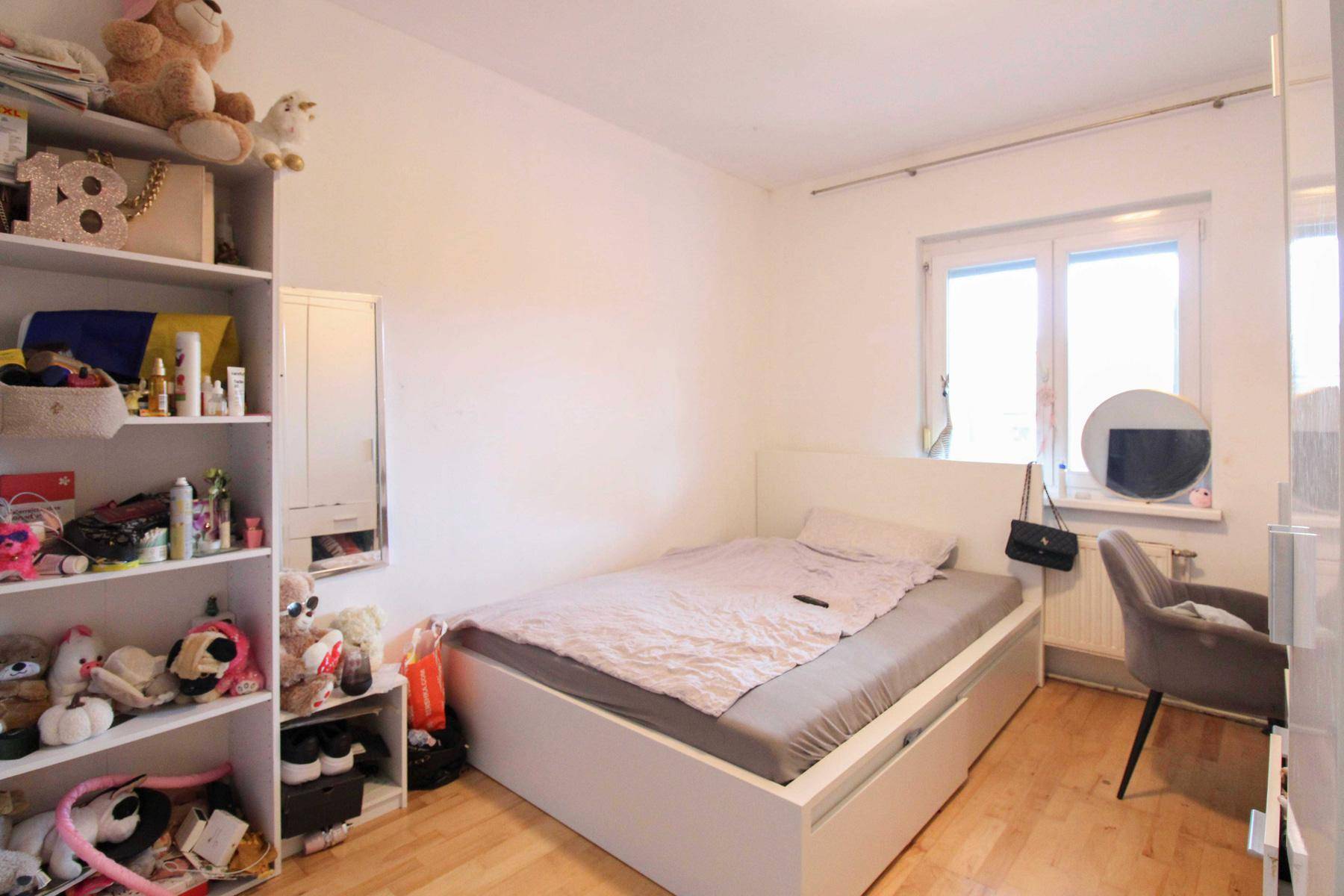 Kinderzimmer mit Holzboden, Fenster und praktischem Stauraum unter dem Bett.