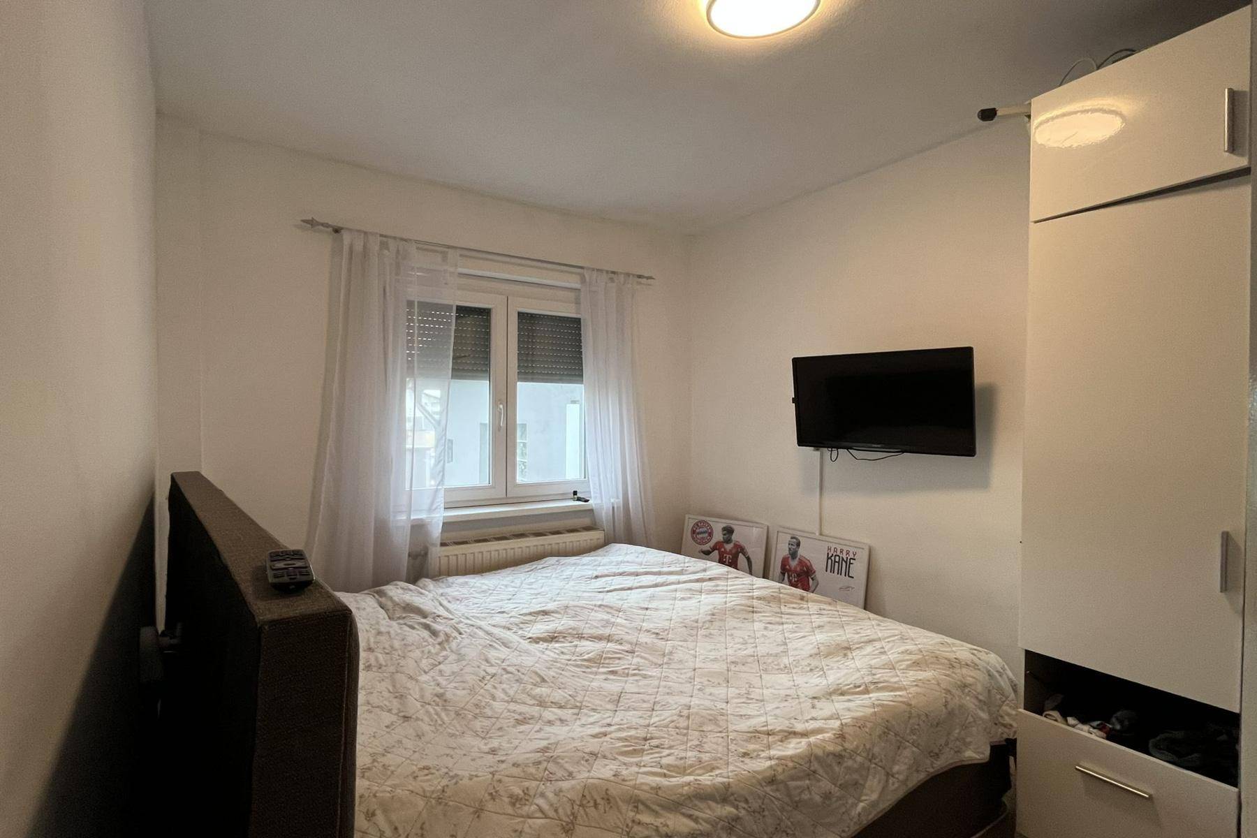 Gemütliches Schlafzimmer mit Doppelbett, Kleiderschrank und Fernseher an der Wand.