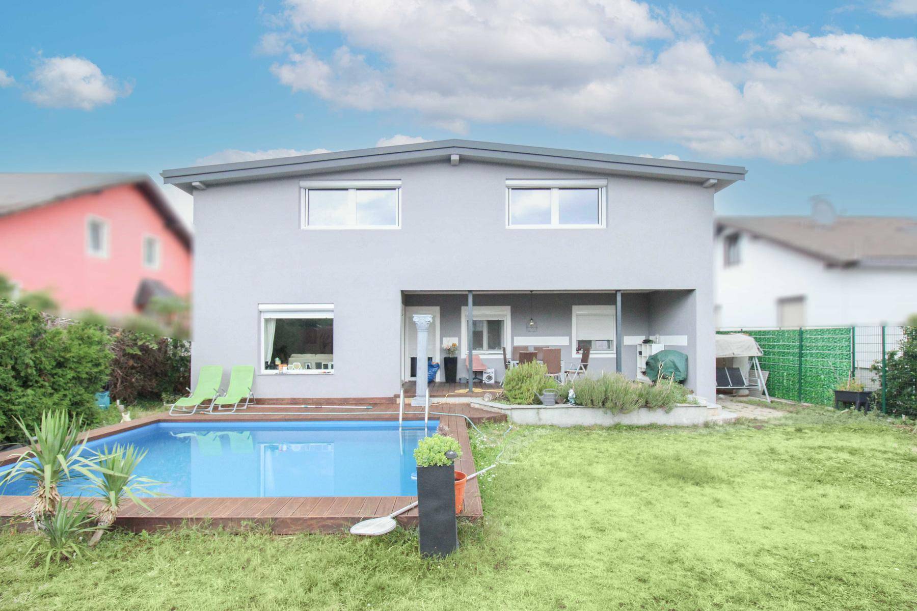 Gepflegter Gartenbereich mit Pool, Holzdeck und Sitzgelegenheiten im Freien.