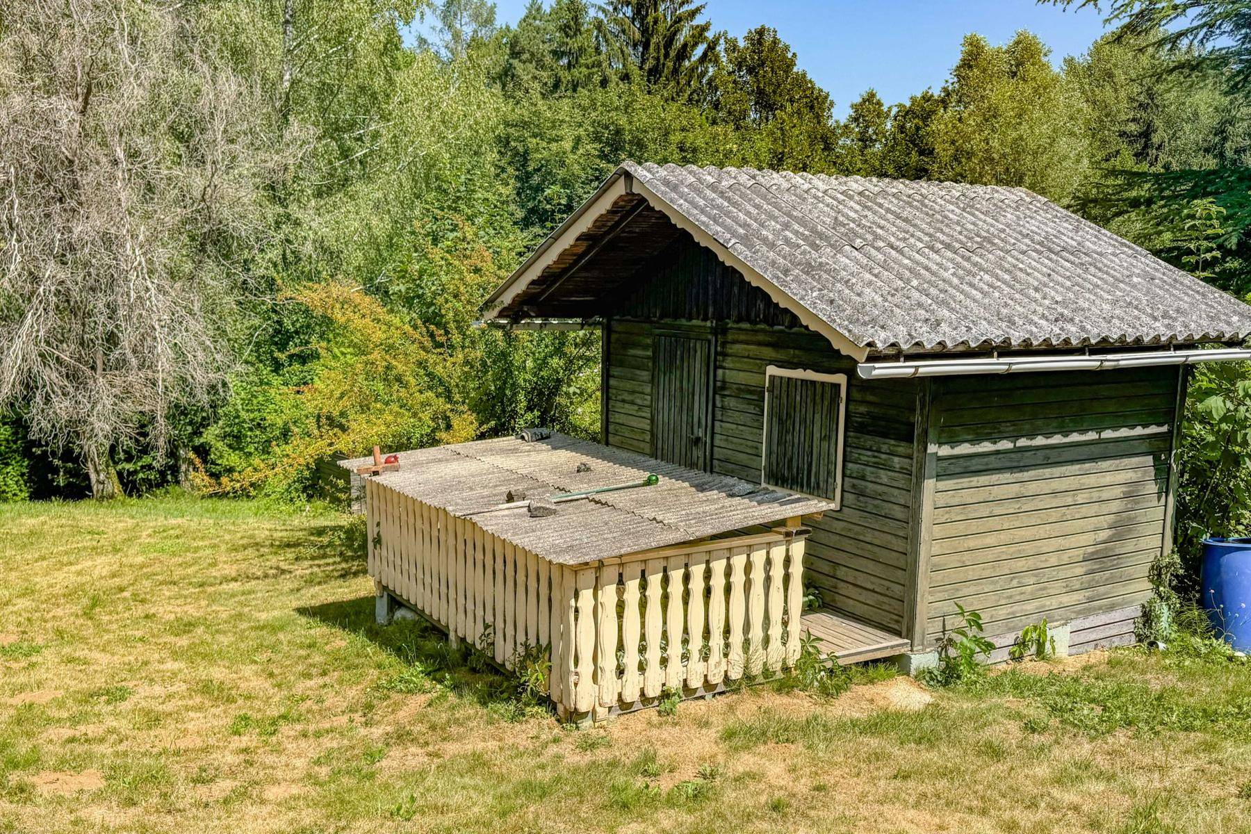Rustikales Gartenhaus mit Holzverkleidung und einem kleinen Vordach auf einer Grünfläche.