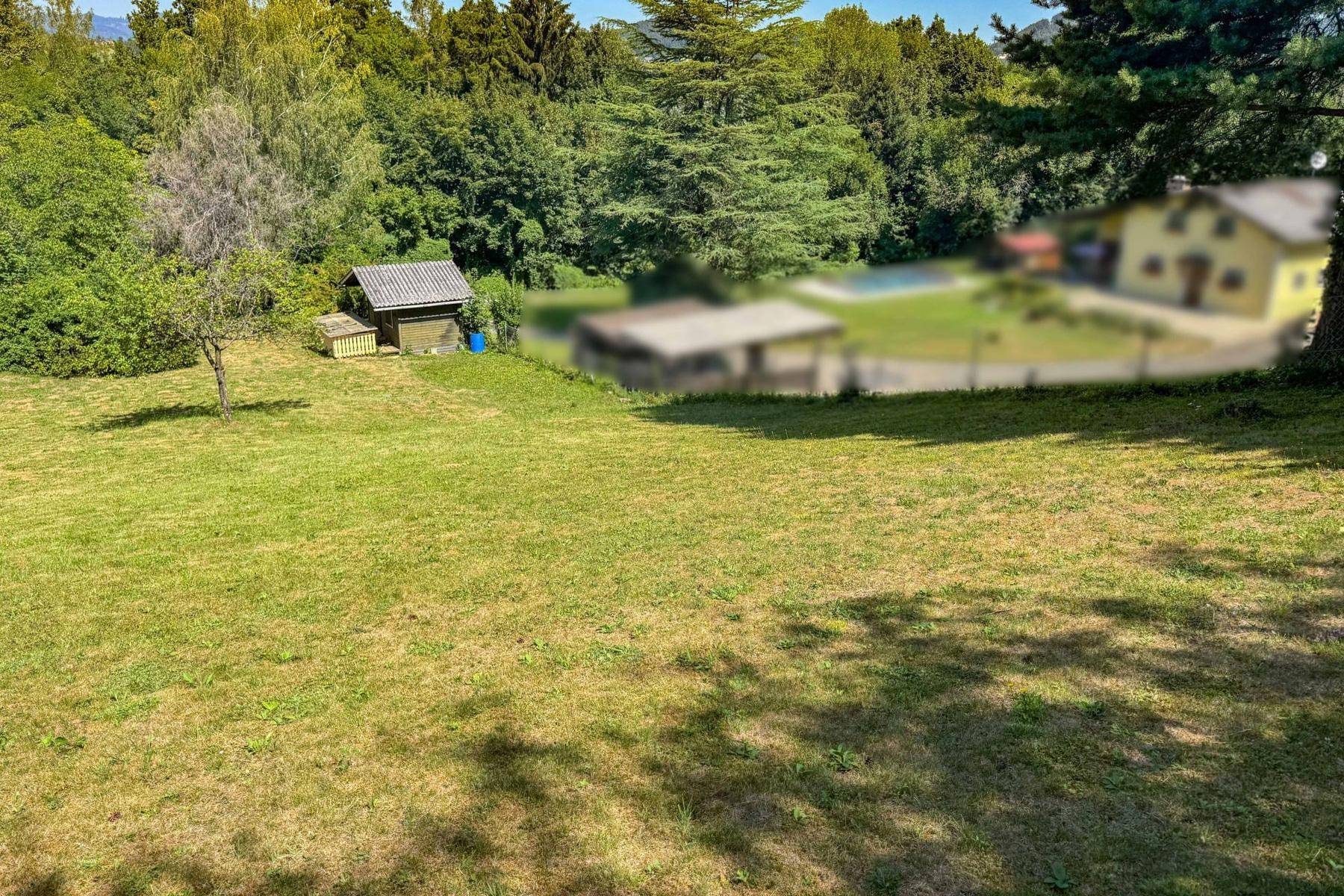 Weitläufige Grünfläche mit Baumbestand und Blick auf weitere Häuser in der Ferne.