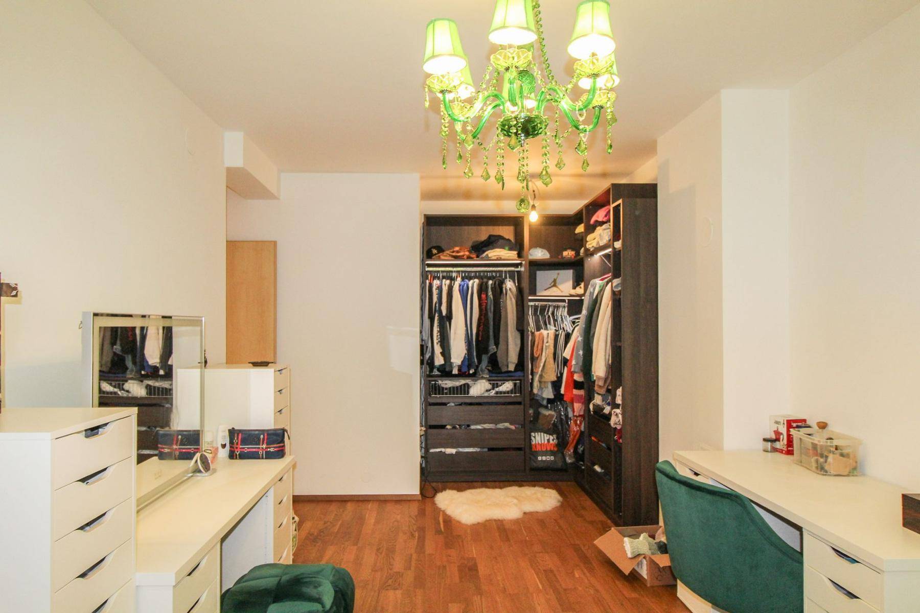 Geräumiger begehbarer Kleiderschrank mit Einbauschränken, Schminktisch und auffälligem Kronleuchter.