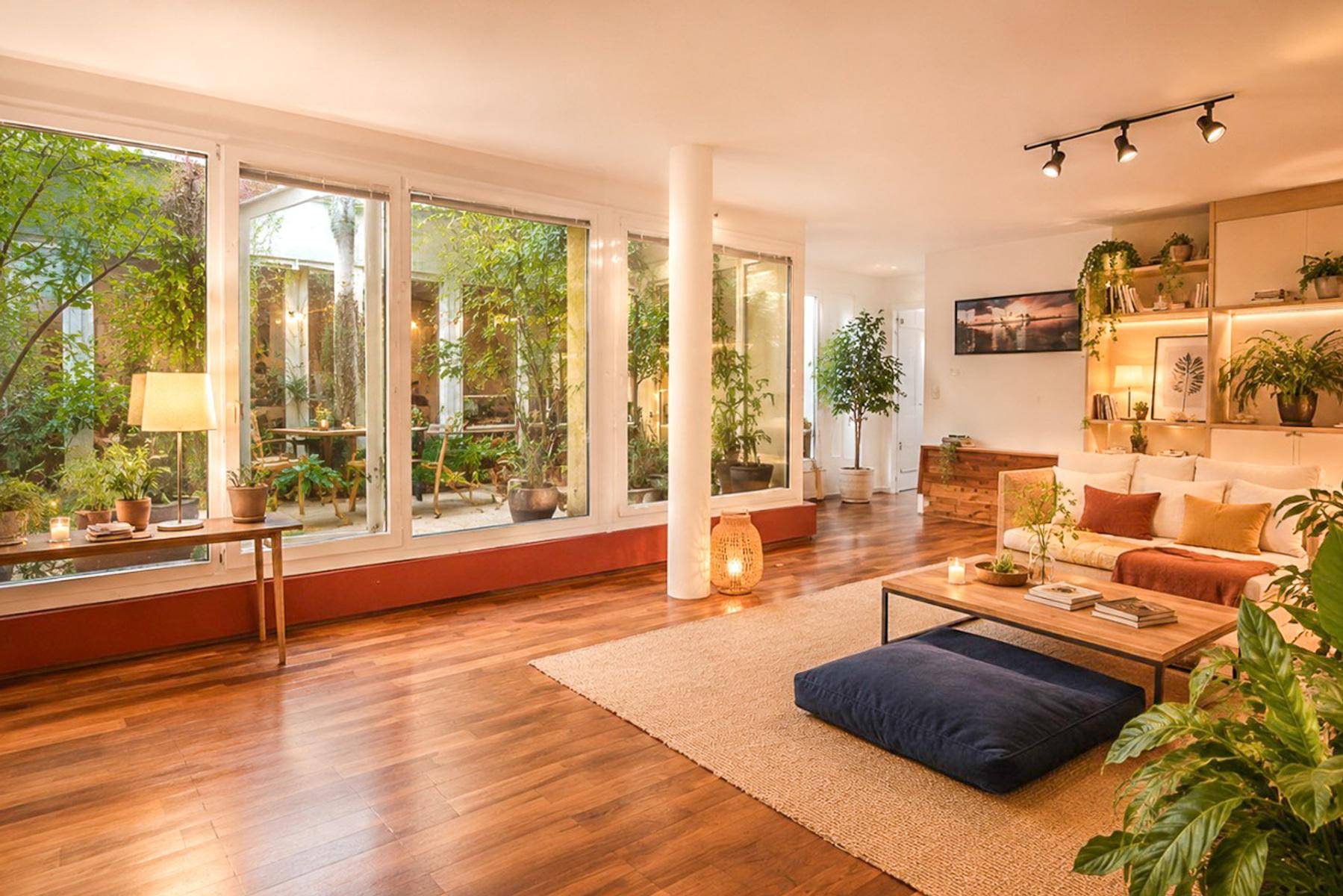 Geräumiges Wohnzimmer mit Holzboden, bequemer Couch und großen Fenstern zum Innenhof.