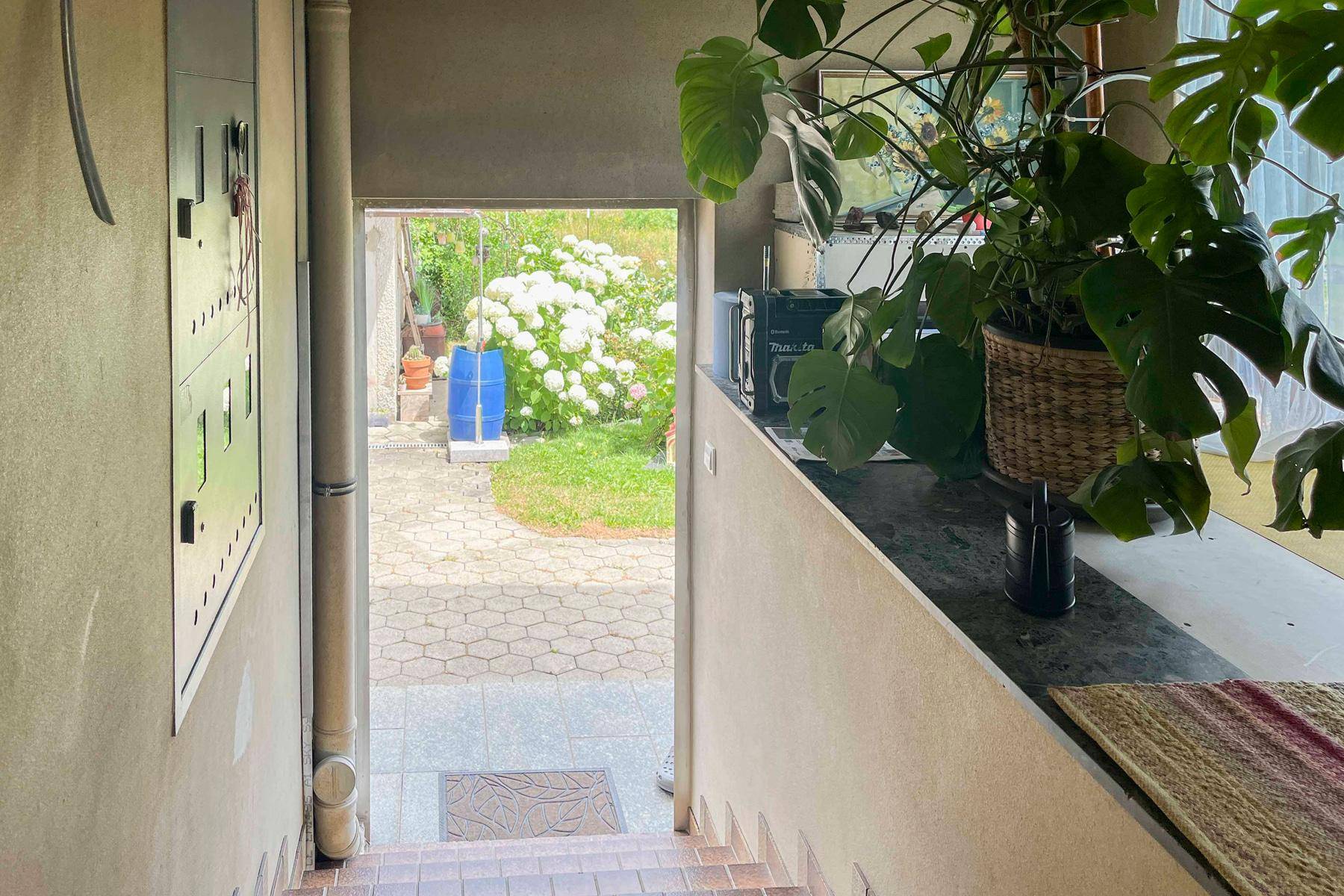 Treppenabgang mit Blick auf den gepflasterten Außenbereich und Garten.