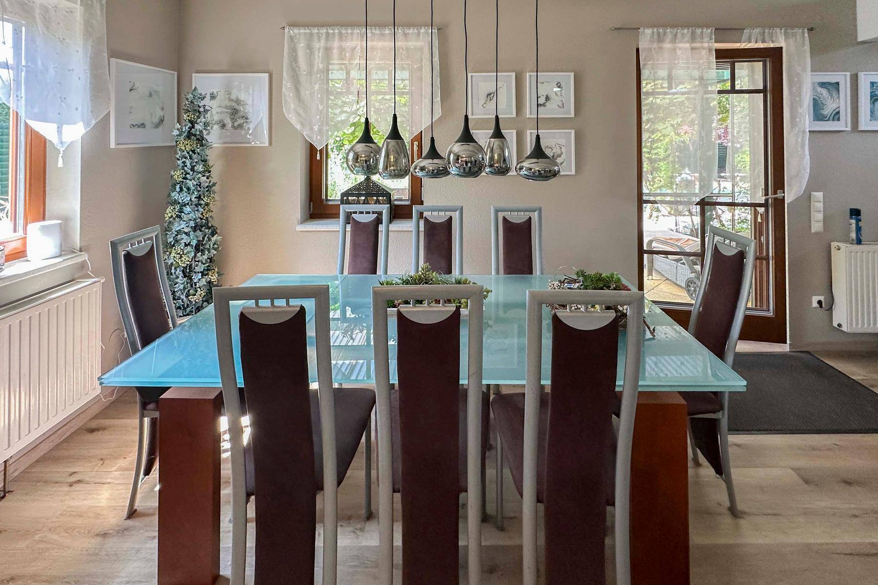 Eleganter Essbereich mit großem Glastisch, modernen Stühlen und Zugang zur Terrasse.