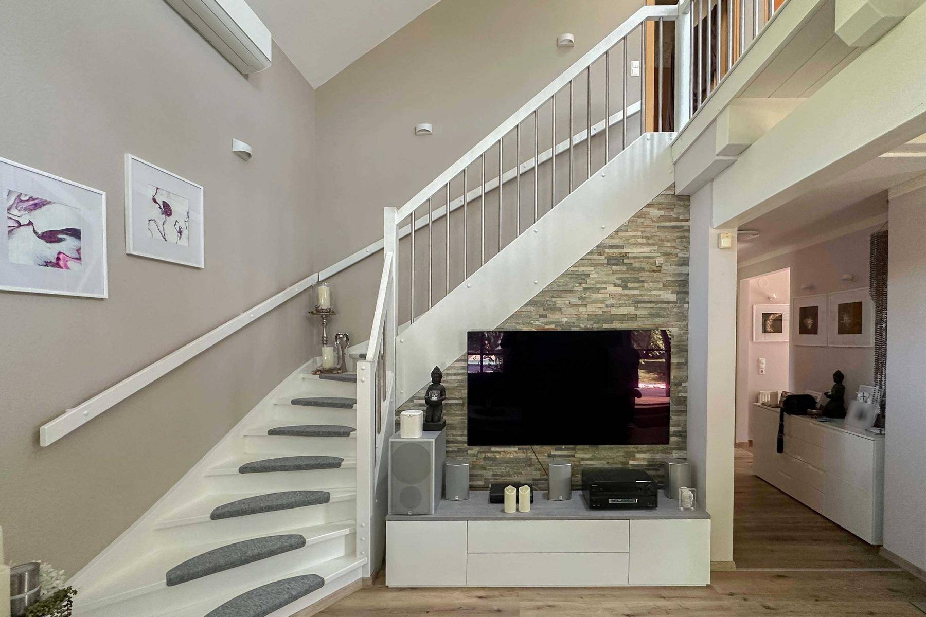 Wohnzimmer mit Treppe zum Obergeschoss, Steinwandakzent und Mediencenter.