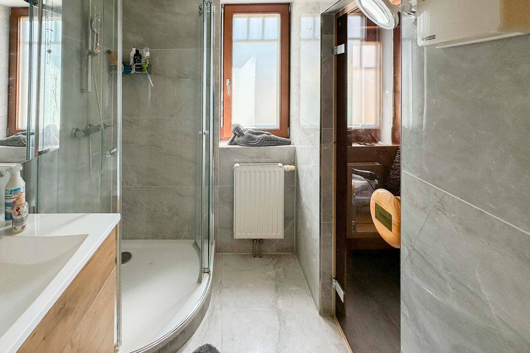 Modernes Badezimmer mit Dusche, Fenster und integrierter Sauna für Wellness.