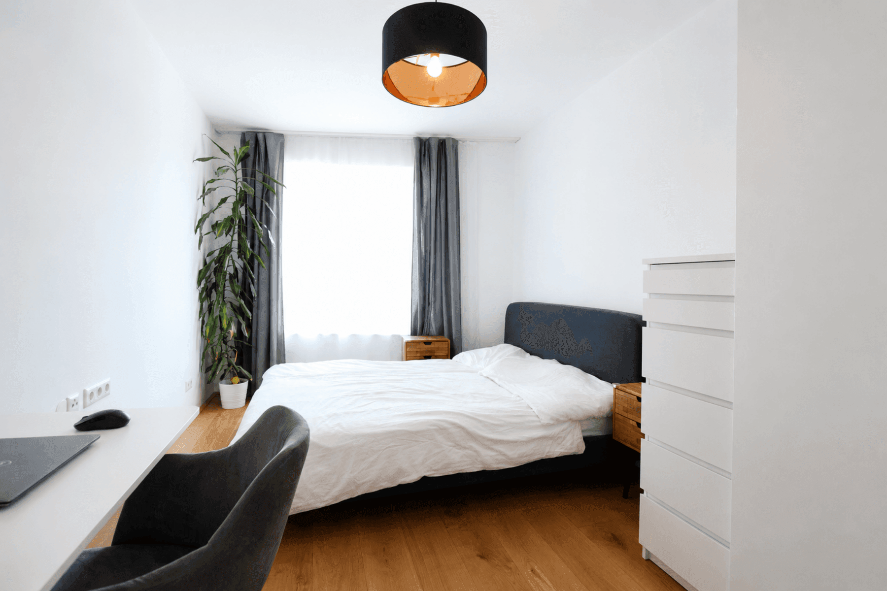 Helles Schlafzimmer mit Holzboden, großem Fenster und minimalistischer Einrichtung.