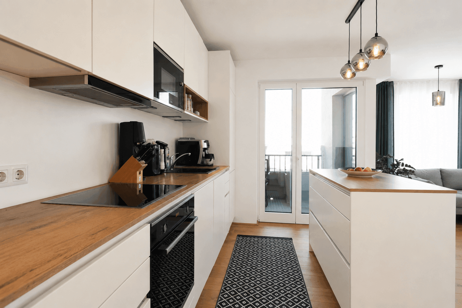 Moderne Einbauküche mit weißen Fronten, Holz-Arbeitsplatte und Induktionskochfeld.