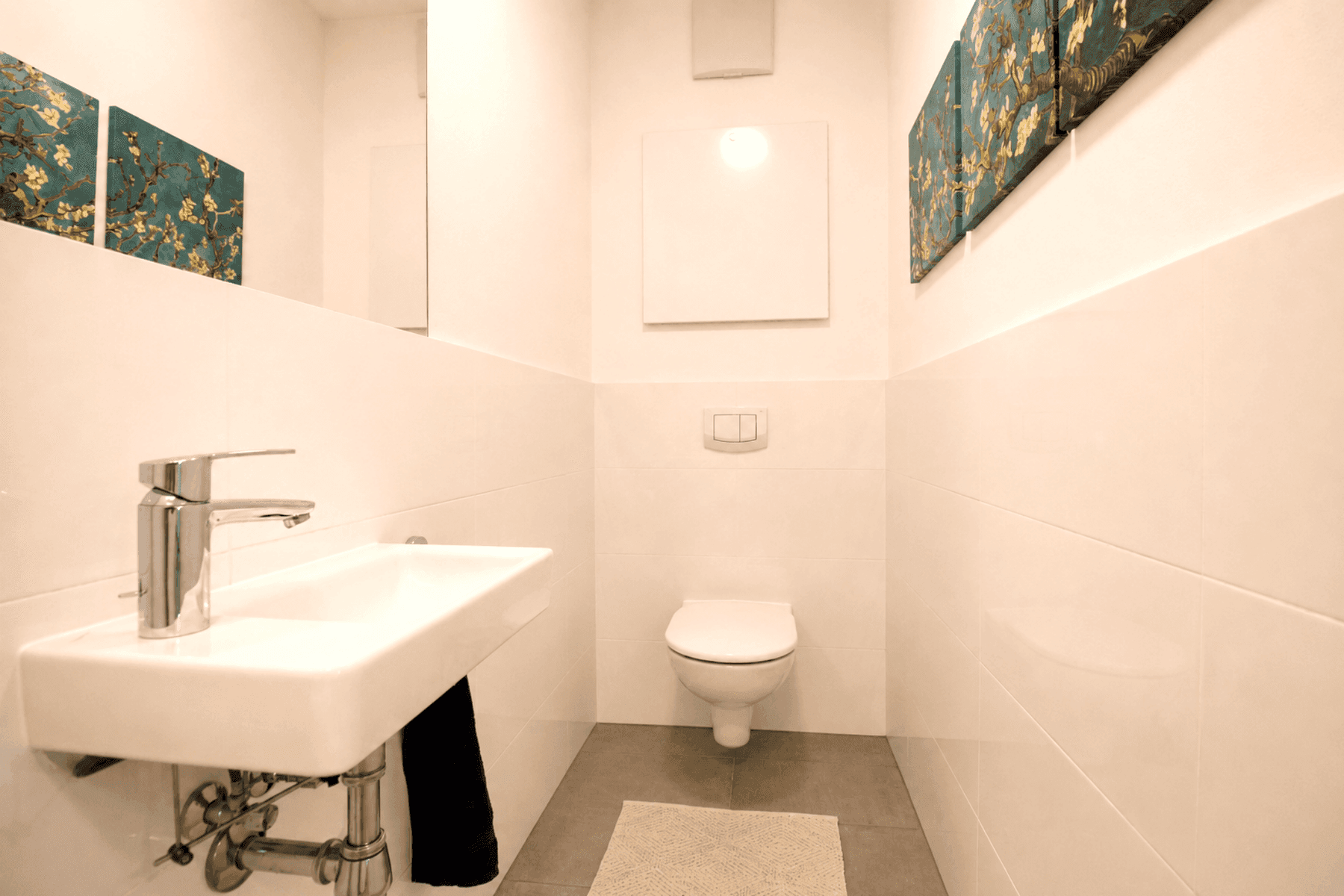 Modernes Gäste-WC mit wandhängendem WC und kleinem Waschbecken.