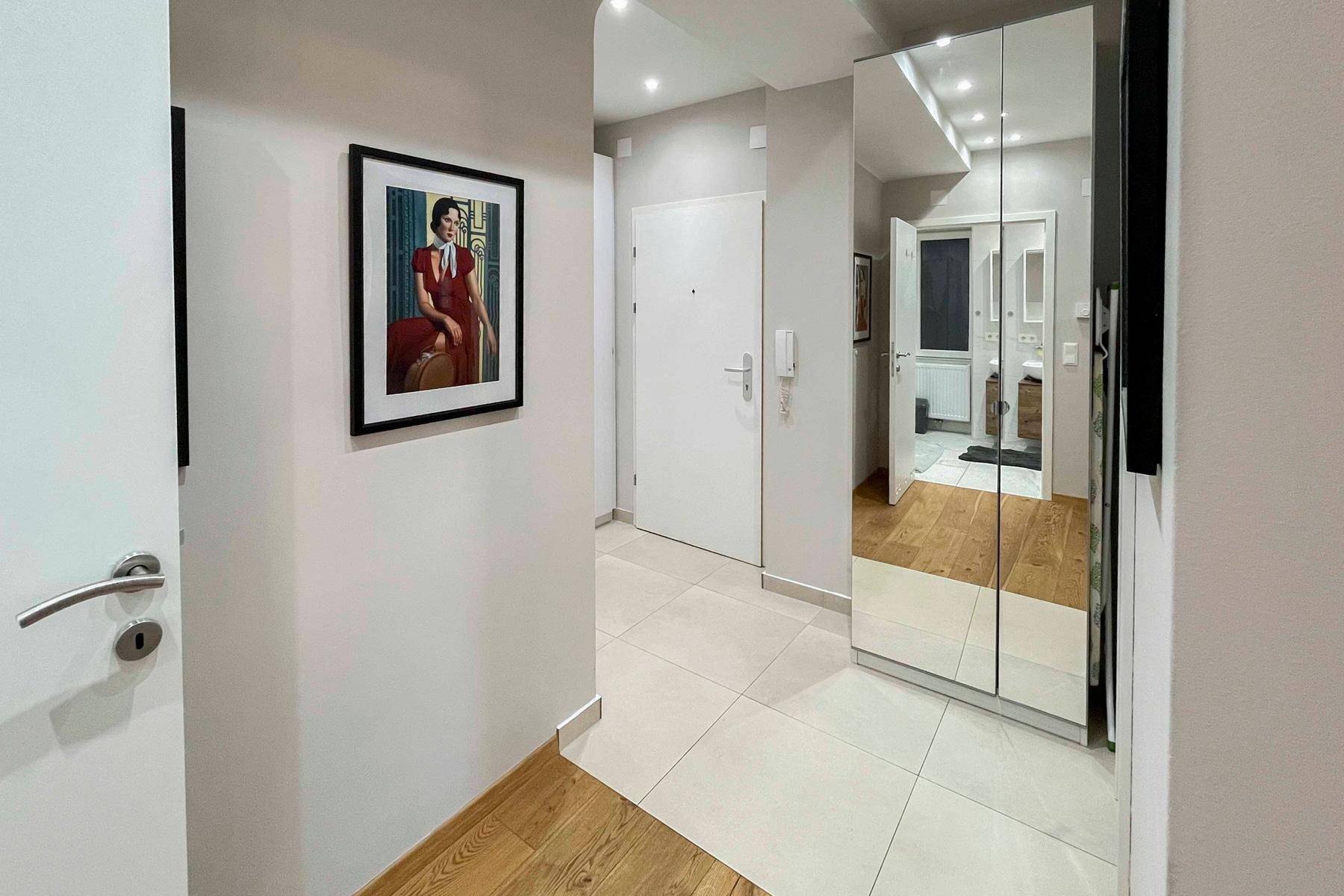 Eingangsbereich mit Fliesenboden, Spiegelgarderobe und heller Wandgestaltung.