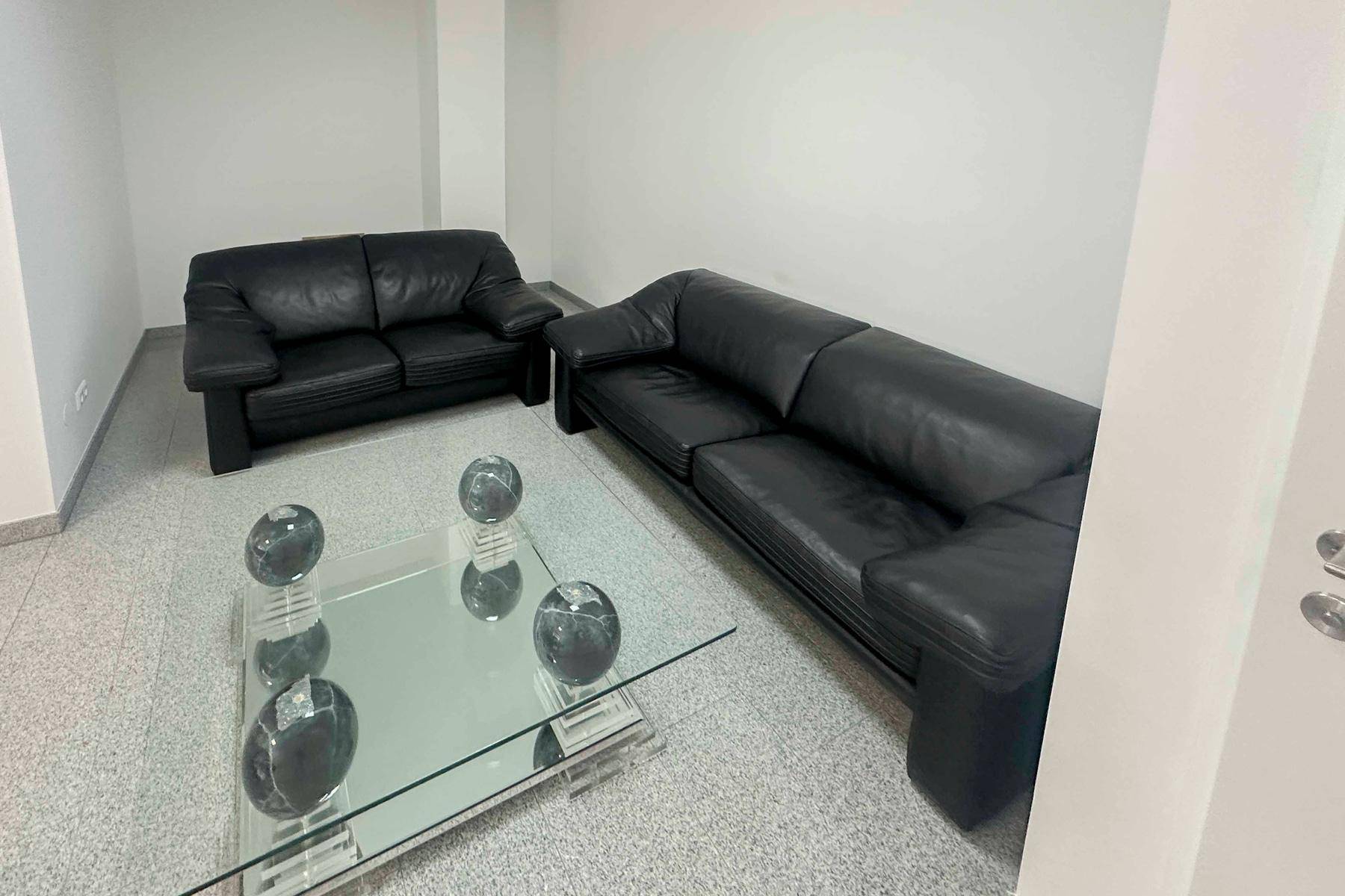 Gemütliche Sitzecke mit schwarzen Ledersofas und einem modernen Glastisch.
