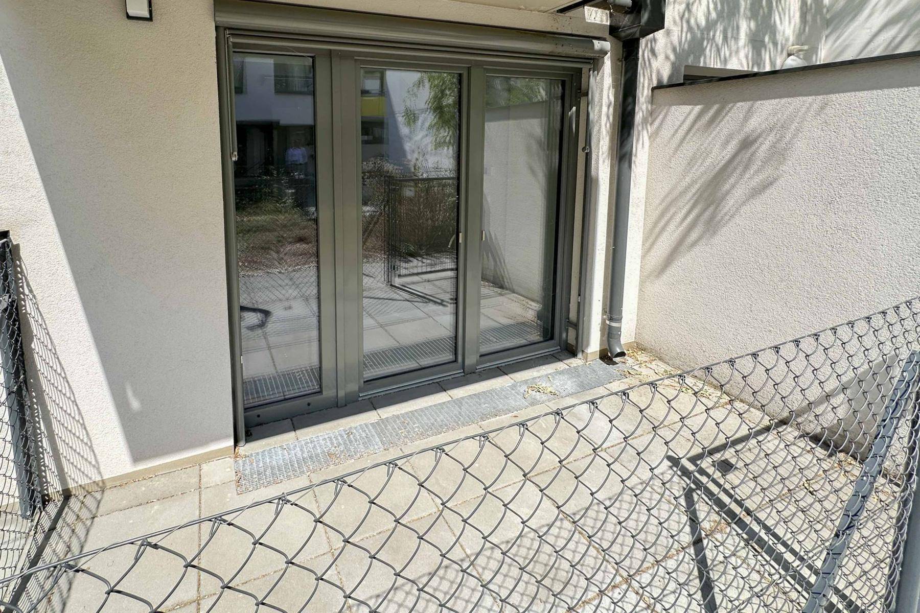 Kleine gepflasterte Terrasse mit Metallzaun und Zugang zum Gebäude.
