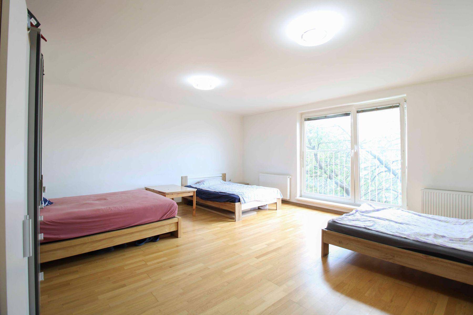 Geräumiges Schlafzimmer mit drei Einzelbetten, Holzrahmen und großem Fenster mit Blick ins Grüne.