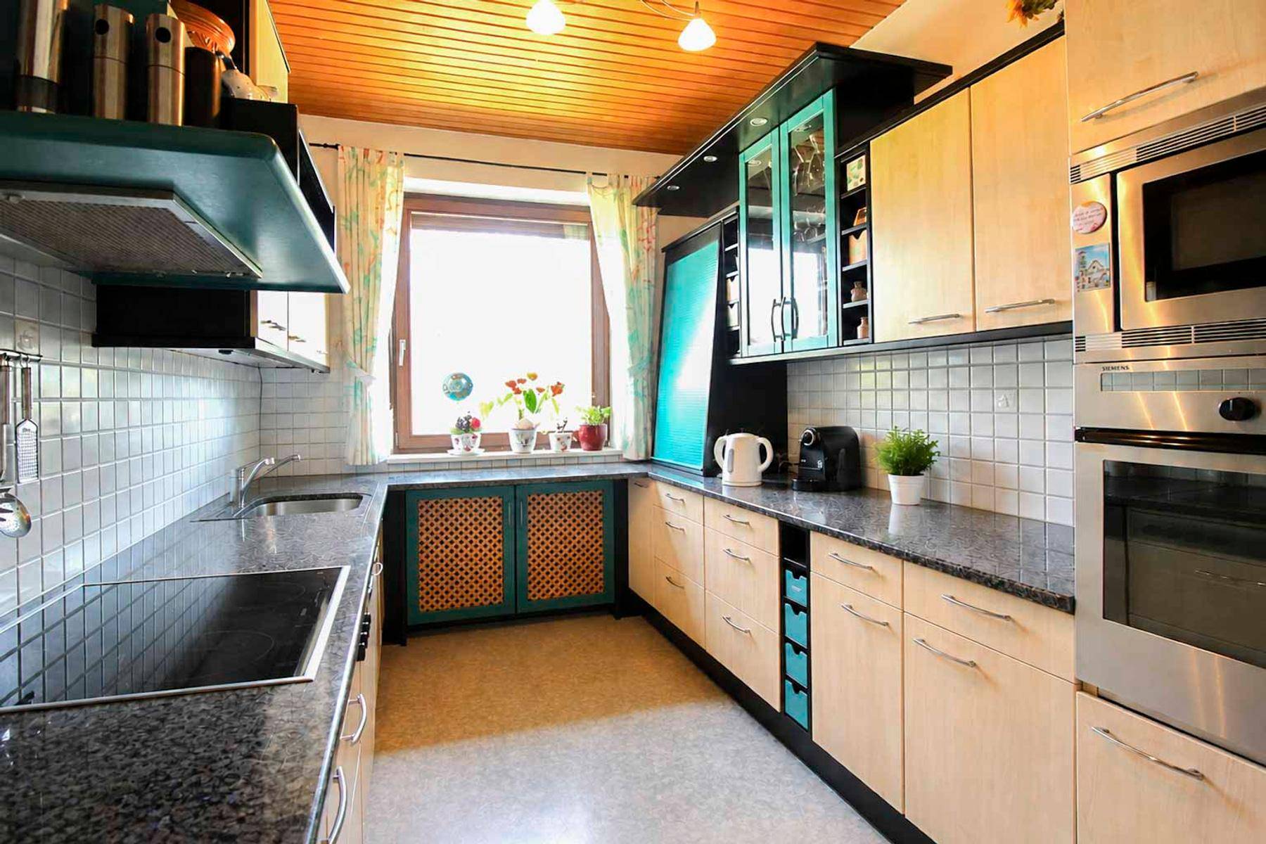 Funktionale Küche mit Granitarbeitsplatten, Holzdecke und integrierten Geräten.