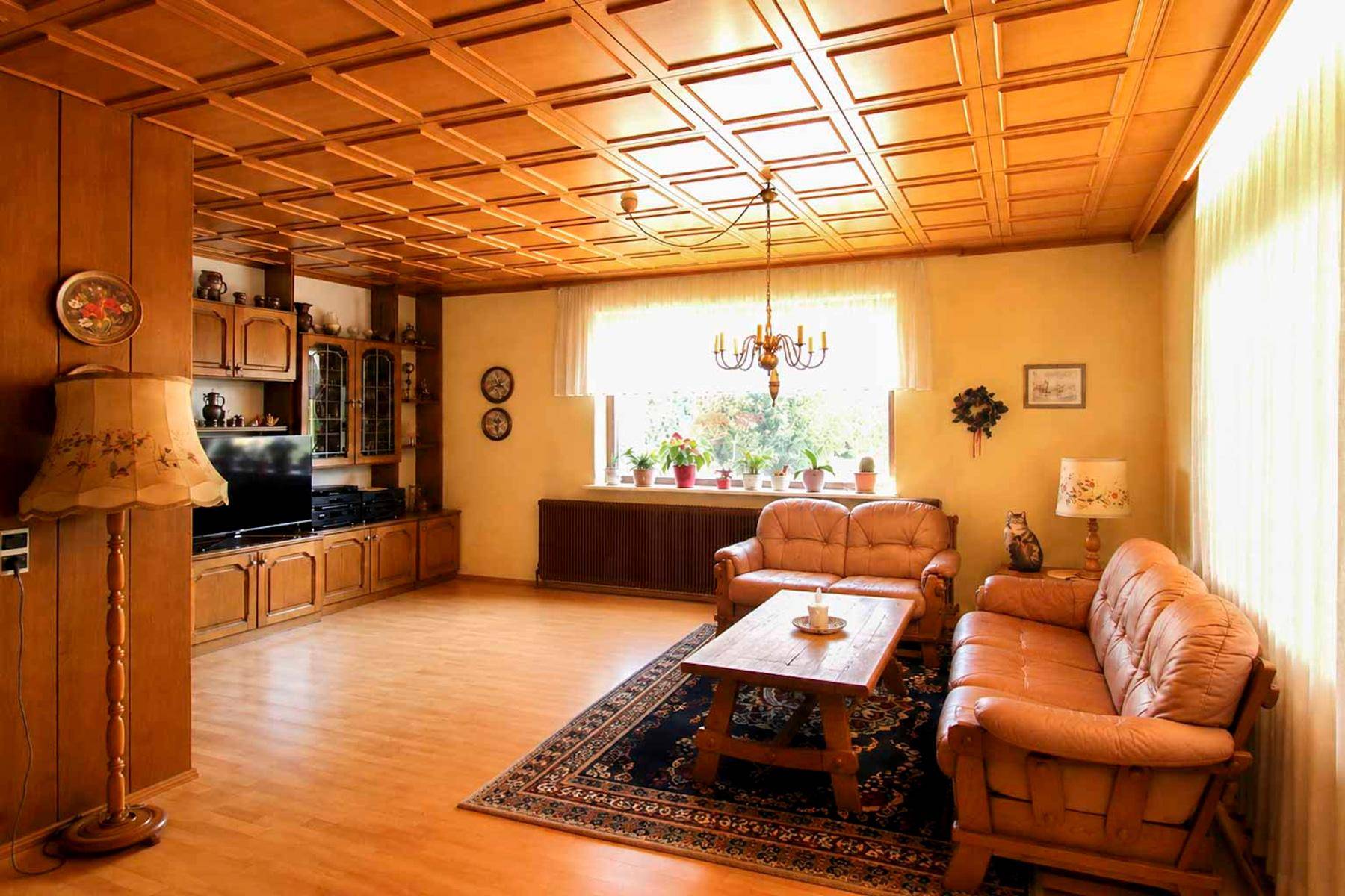 Gemütliches Wohnzimmer mit Holzdecke, Parkettboden und traditionellen Möbeln.