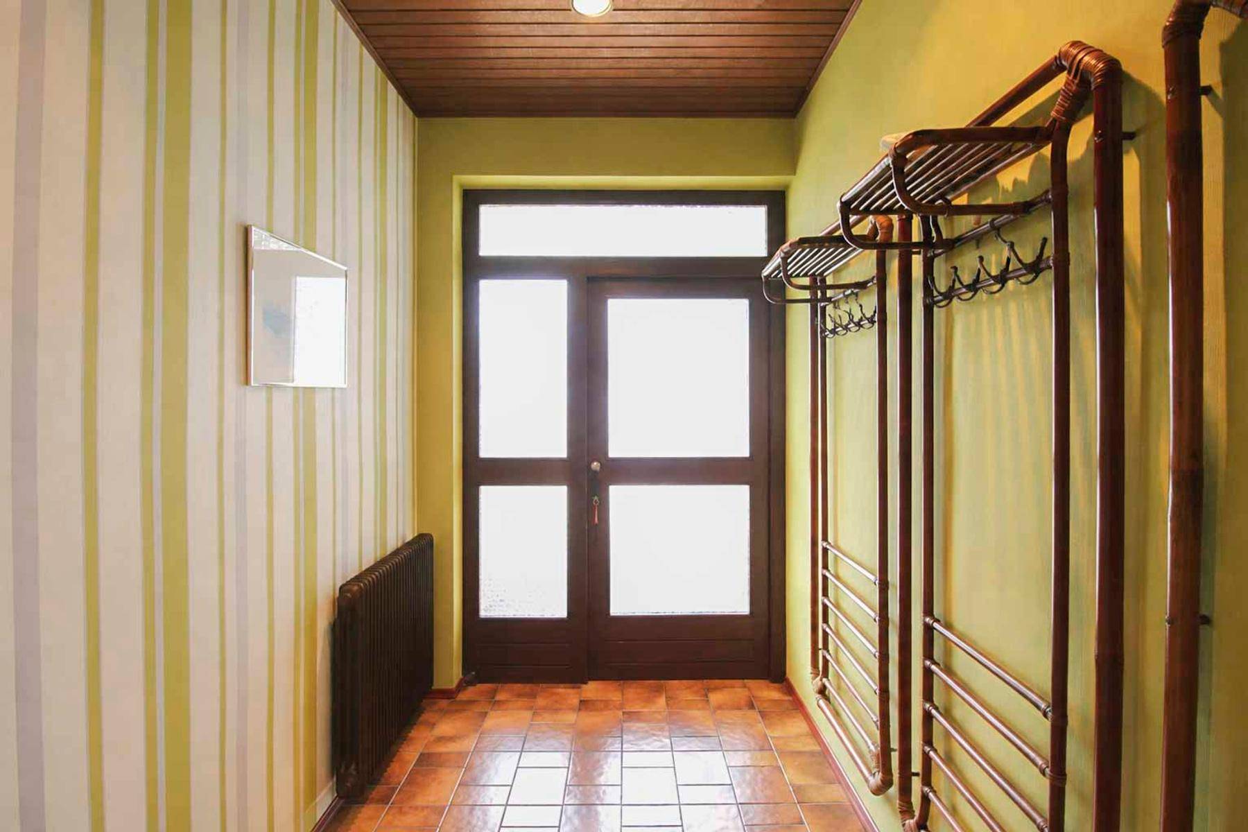 Eingangsbereich mit gestreifter Tapete, Fliesenboden und Garderobe.