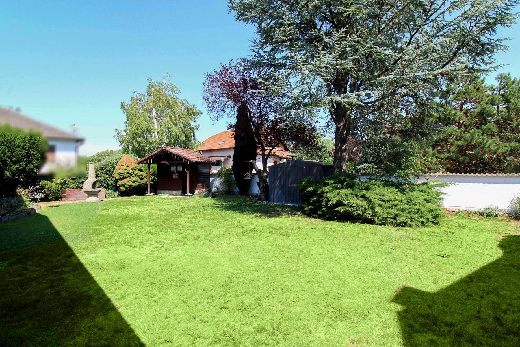 Großer, gepflegter Garten mit Rasenfläche, Bäumen und Gartenhaus.