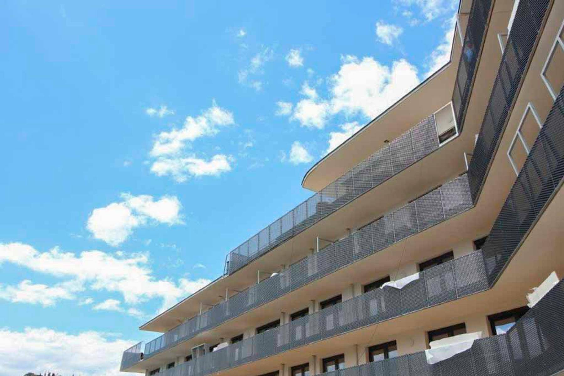 Ansicht der modernen Wohnanlage unter blauem Himmel mit vielen Balkonen und klaren Linien.