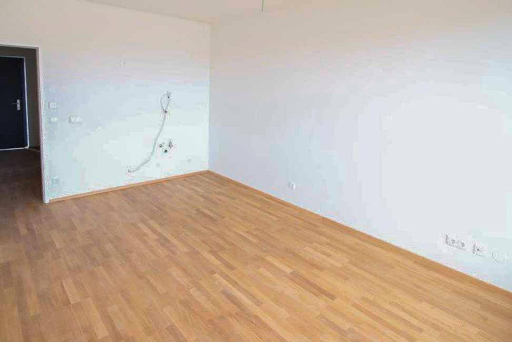 Geräumiger, heller Raum mit Holzboden und weißen Wänden, bereit für die Einrichtung.