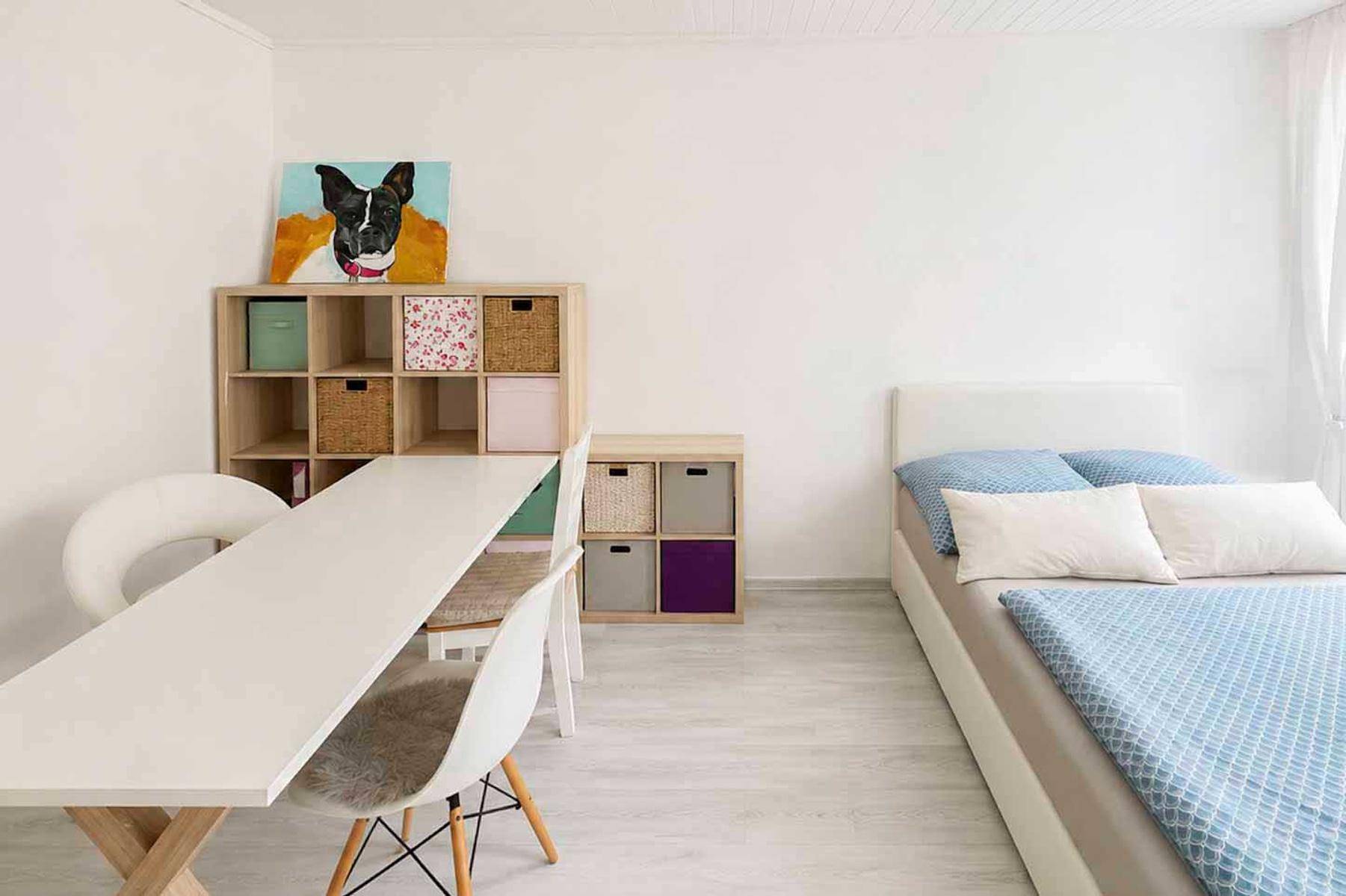 Geräumiges Schlafzimmer mit Esstisch, Regal und hellem Laminatboden.