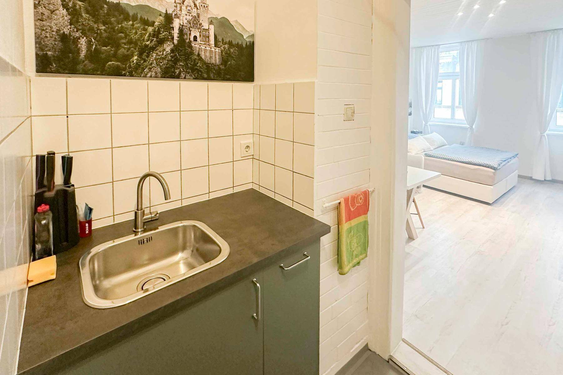 Küchenzeile mit Spüle, Fliesenrückwand und Durchblick zum Schlafbereich.