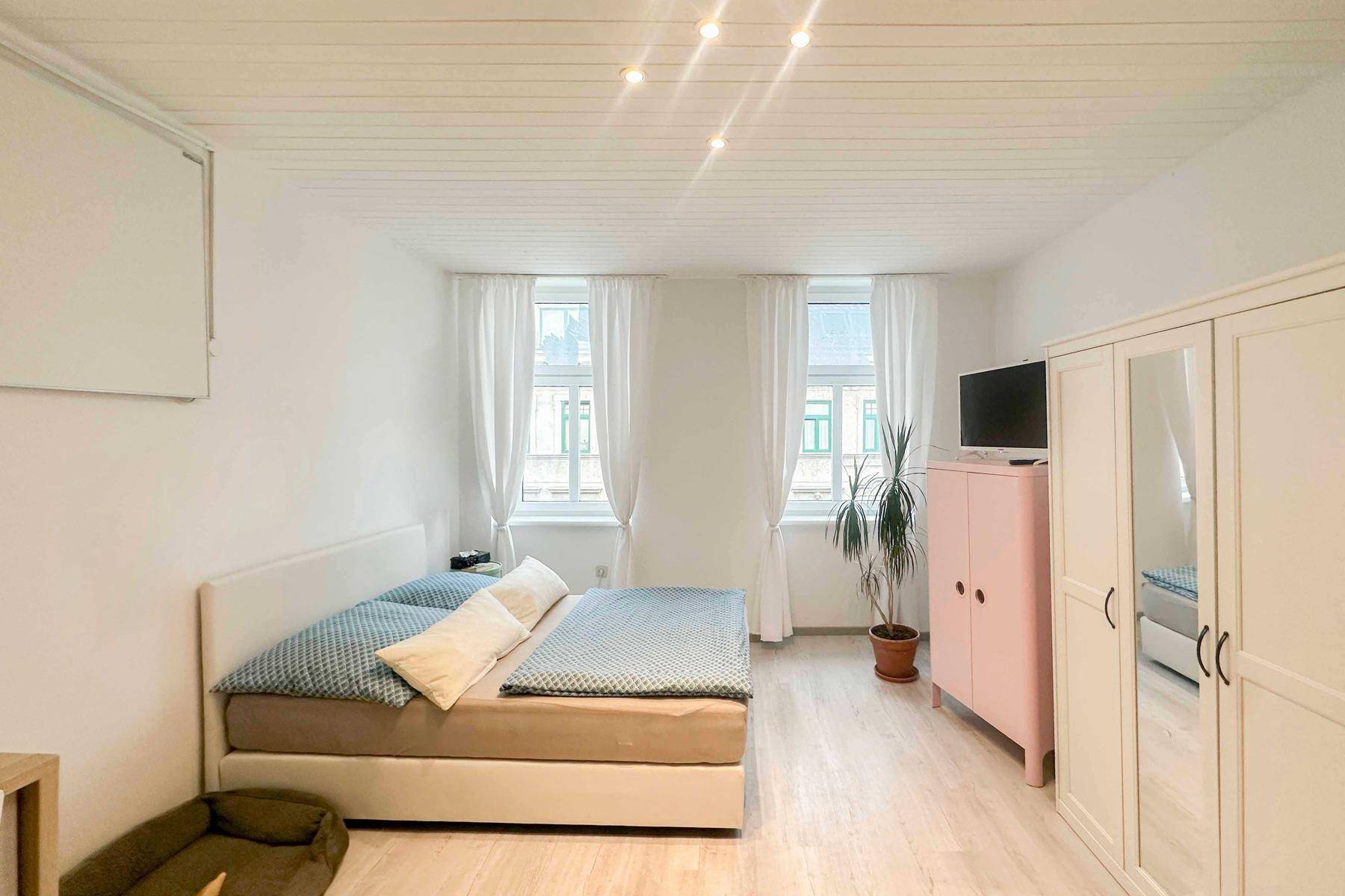 Gemütliches Schlafzimmer mit weißer Holzdecke, Doppelbett und Blick nach draußen.
