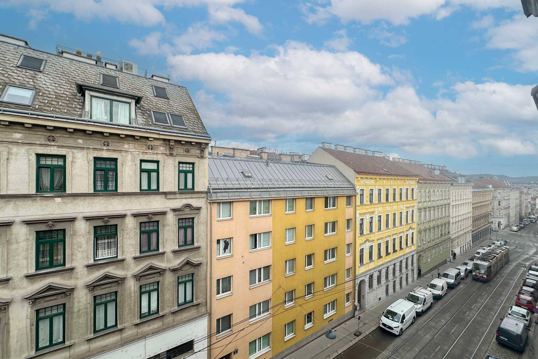 Blick auf eine belebte Stadtstraße mit historischen und modernen Gebäuden.