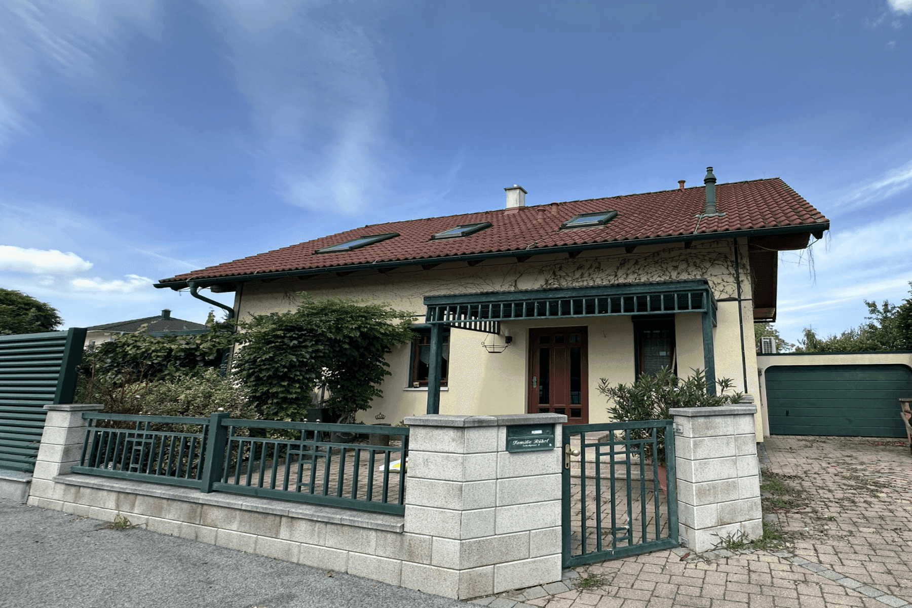 Charmantes Einfamilienhaus mit Vorgarten, Zaun und Garagenzufahrt.