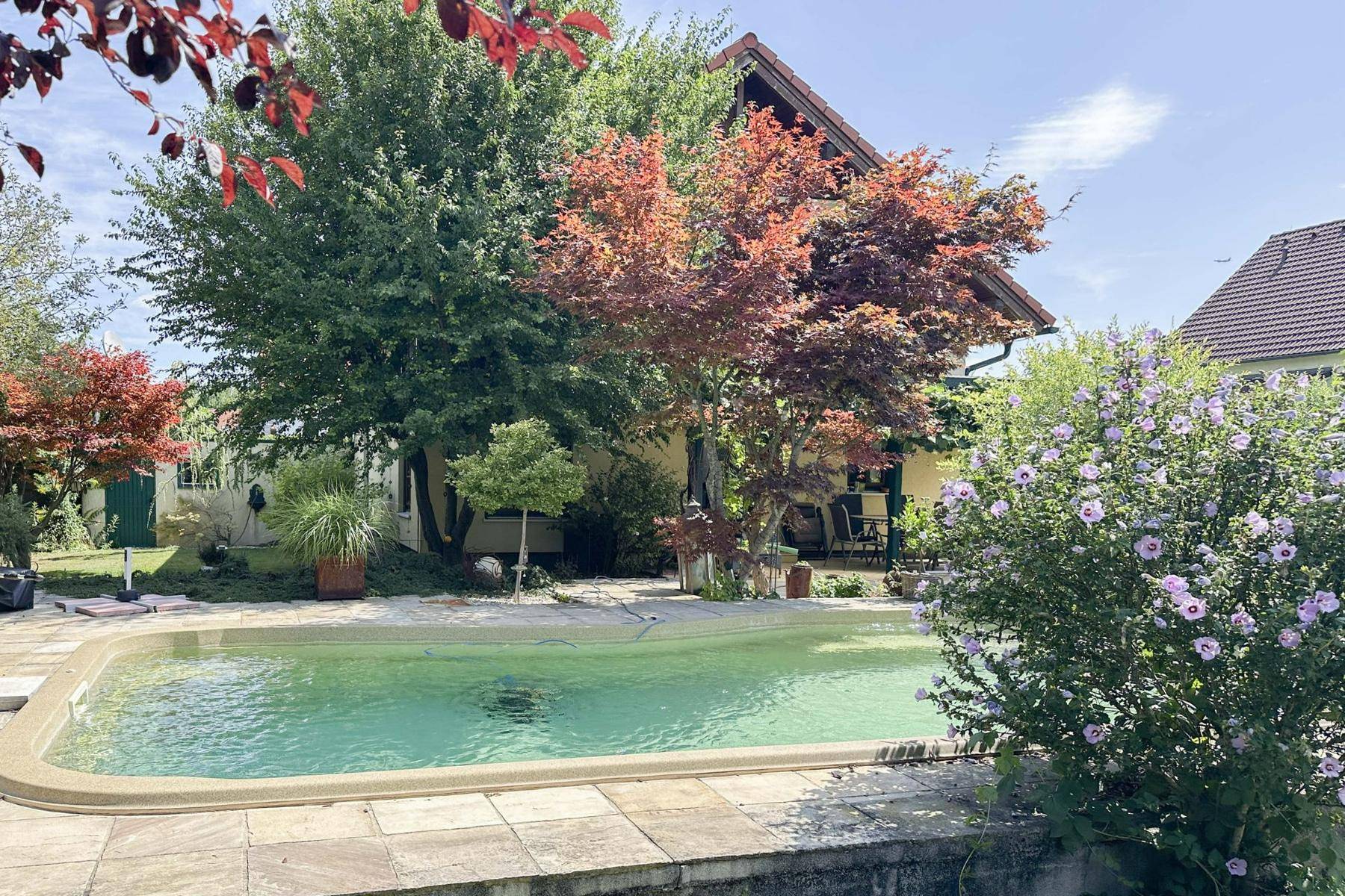 Weitläufiger Garten mit Pool, Terrasse und Blick auf das charmante Wohnhaus.