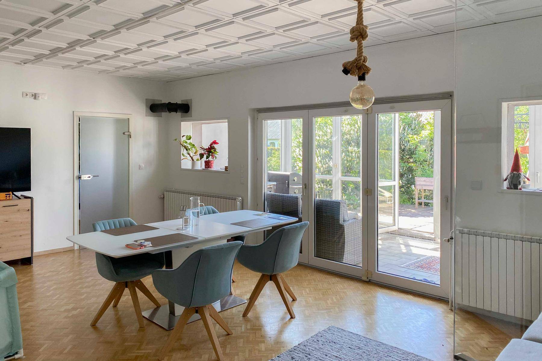 Heller Wohn- und Essbereich mit Parkettboden, dekorativer Decke und Zugang zur Terrasse.