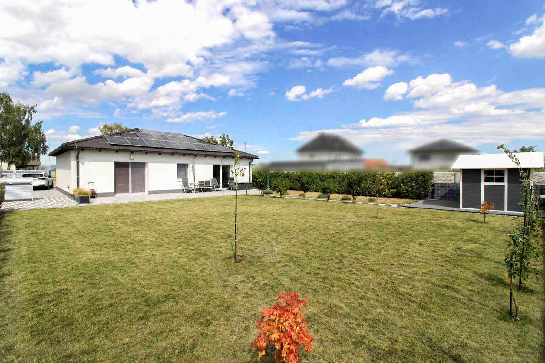 Großer, gepflegter Garten hinter dem Haus mit Rasenfläche und kleinem Gartenhaus.