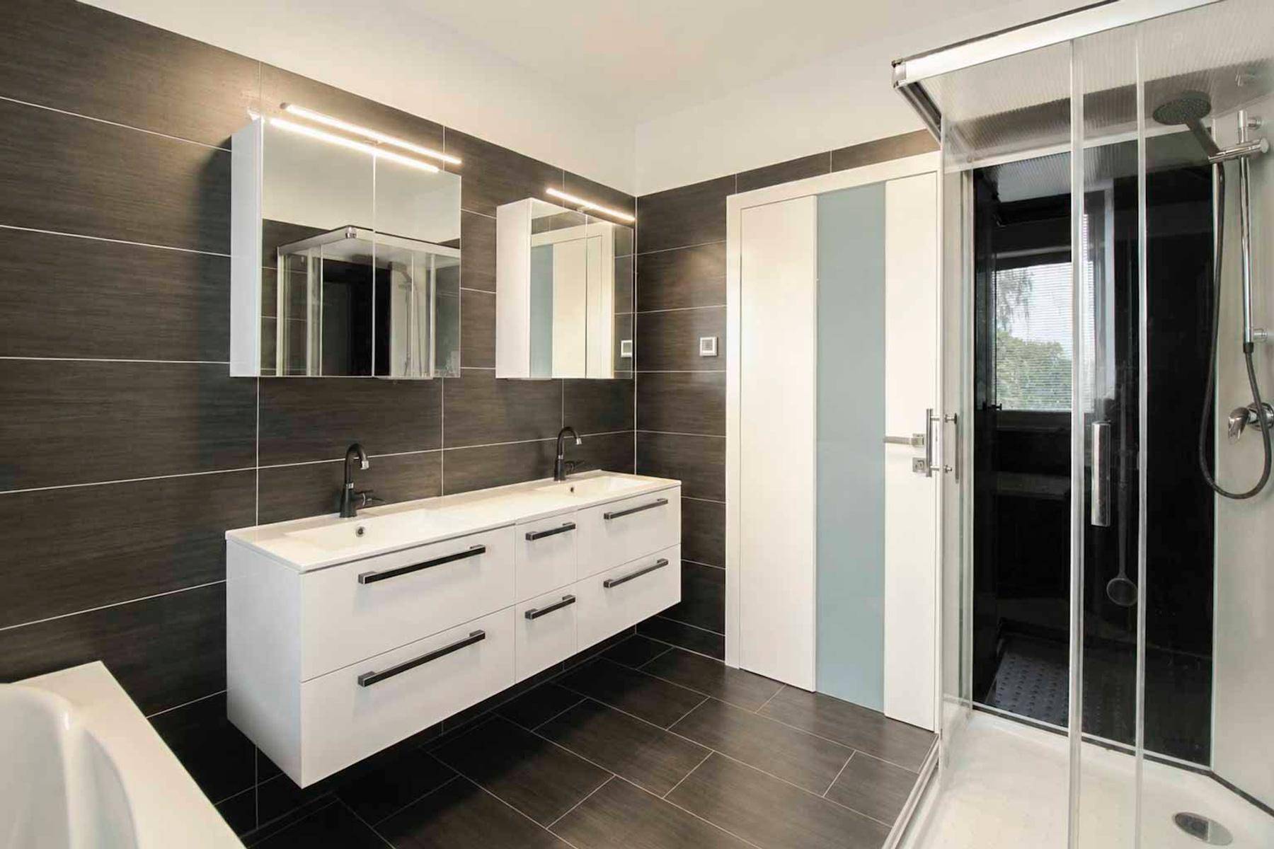 Geräumiges Badezimmer mit Doppelwaschbecken, großer Dusche und modernen Spiegelschränken.