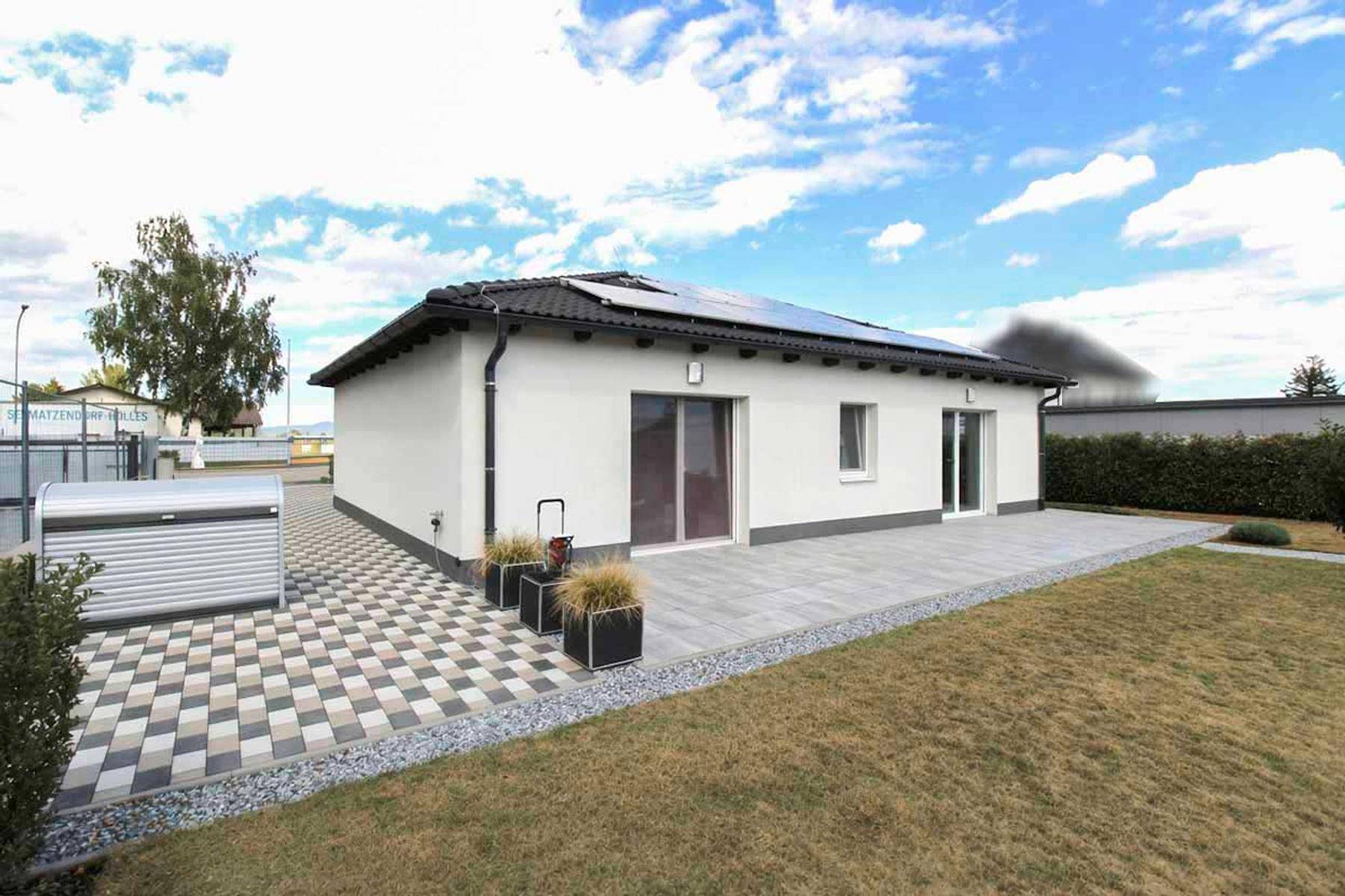Geräumige Terrasse am Haus mit Pflastersteinen und Zugang zum grünen Garten.
