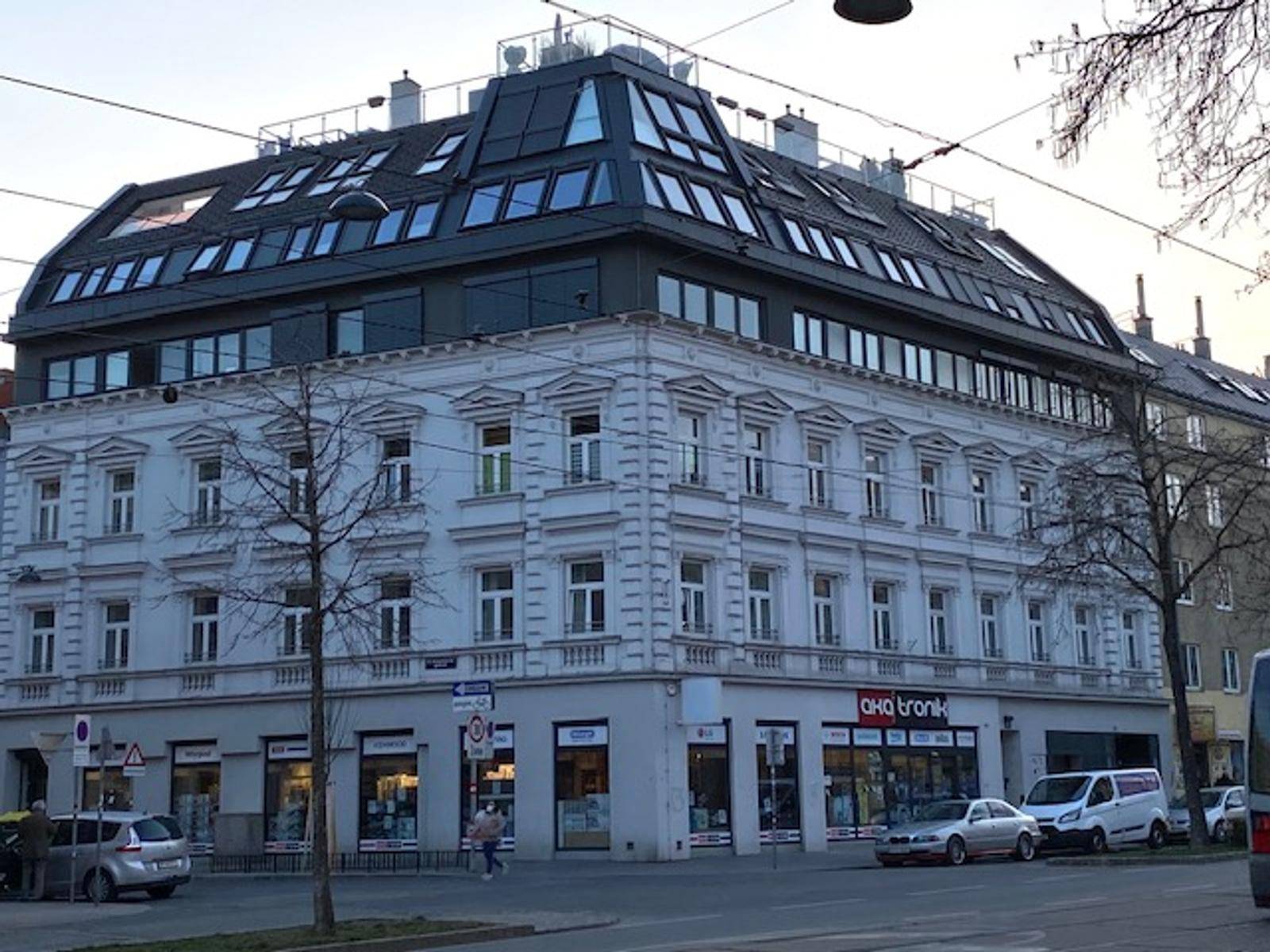 Gebäude mit klassischer Fassade und modernem Dachausbau, der sich harmonisch in die Stadtlandschaft einfügt.