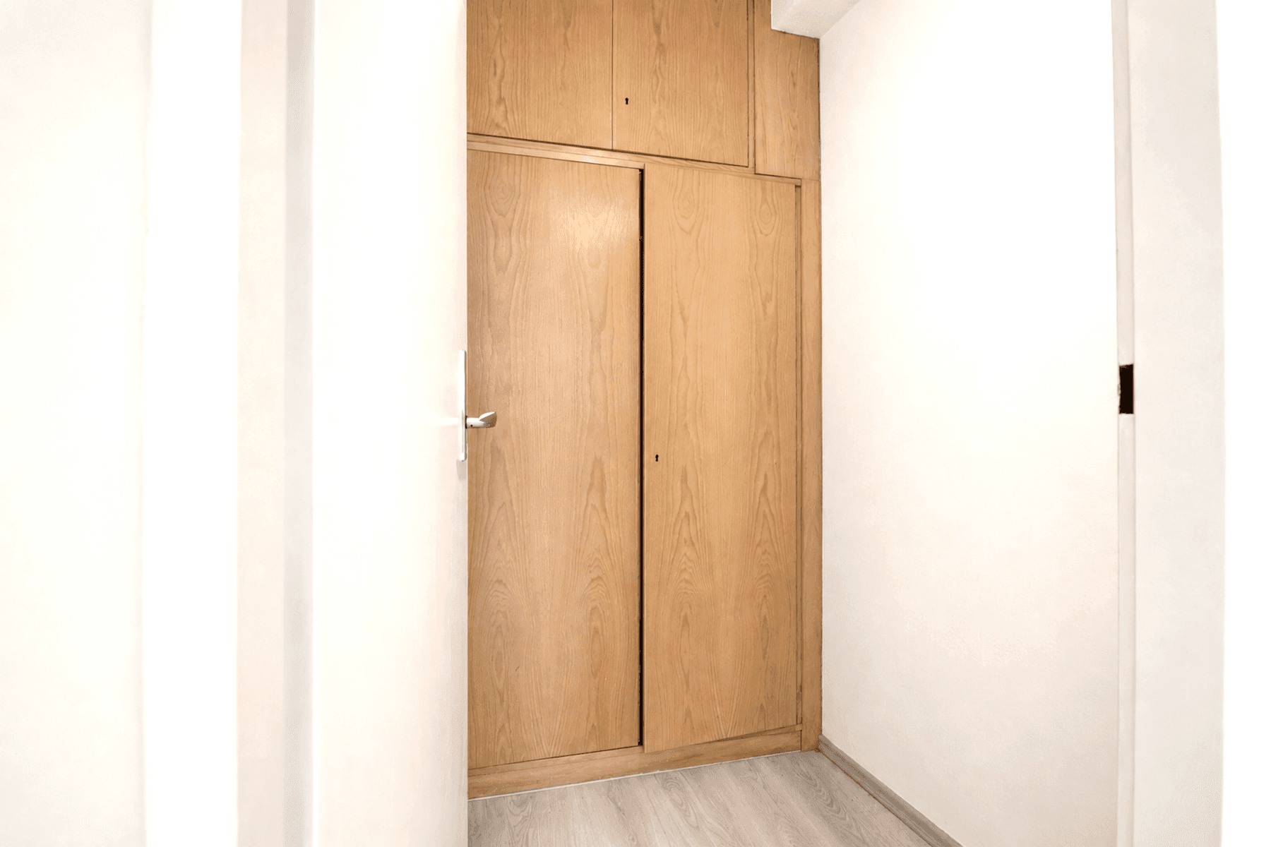 Einbauschrank mit Holzfronten und Schiebetüren in einem hellen Flurbereich.