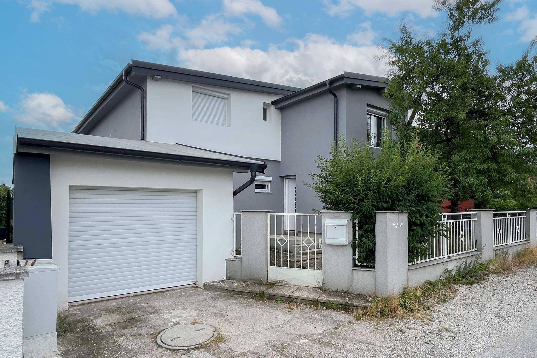 Vorderansicht des modernen Hauses mit integrierter Garage und gepflegter Einfahrt.