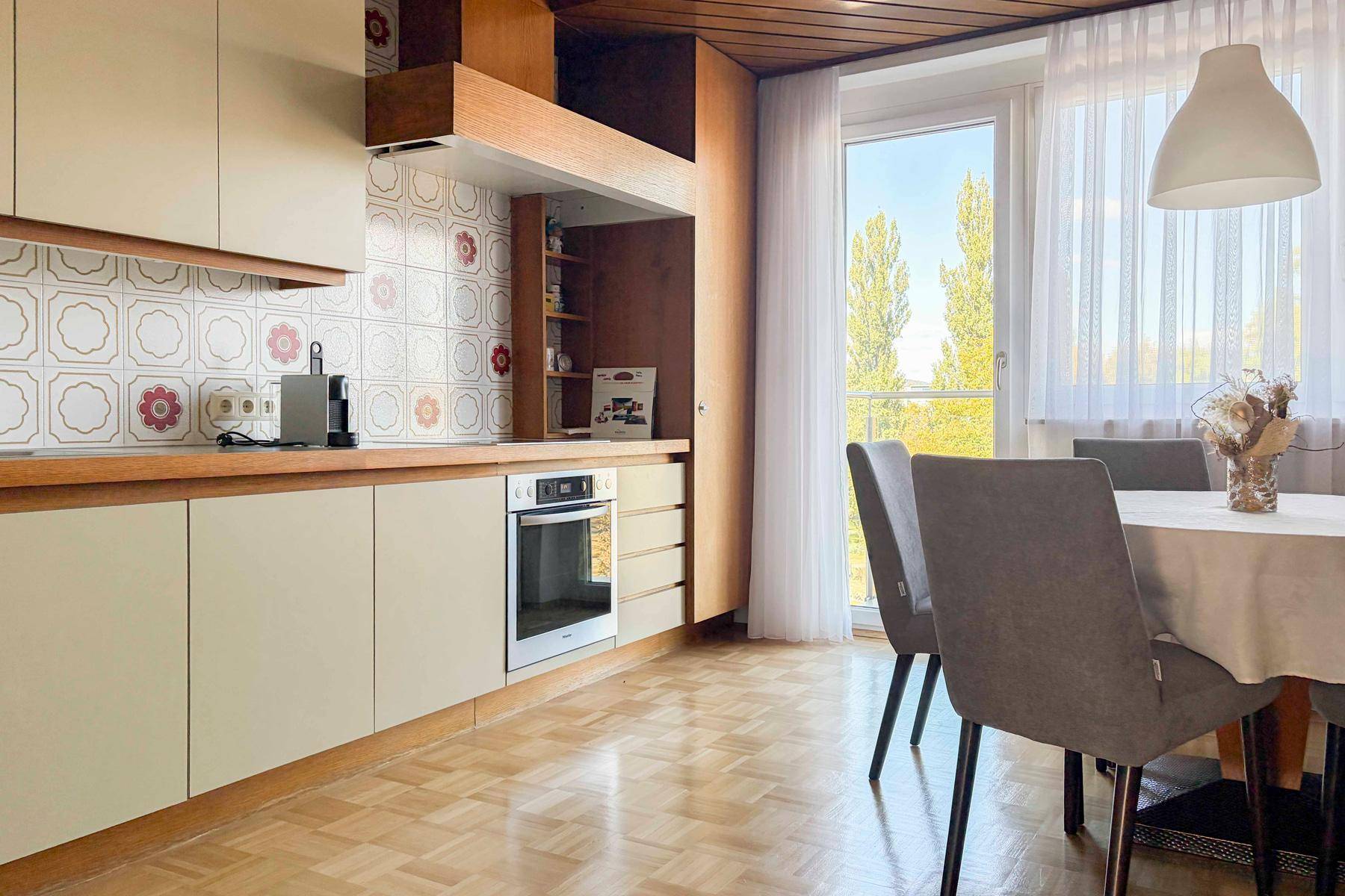 Funktionale Küche mit Essbereich, Holzvertäfelung und Fenster mit viel Tageslicht.