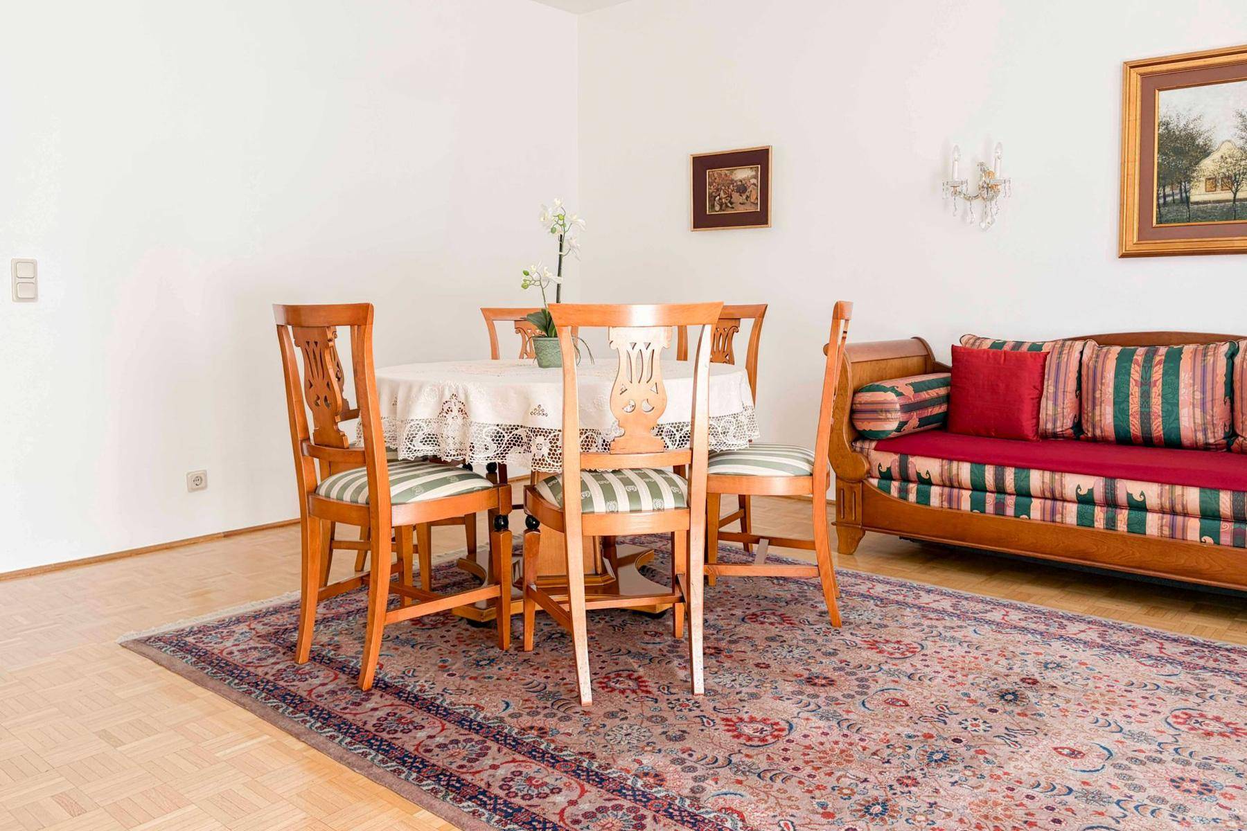 Traditioneller Essbereich mit Holztisch, Stühlen und einem Sofa im Hintergrund.