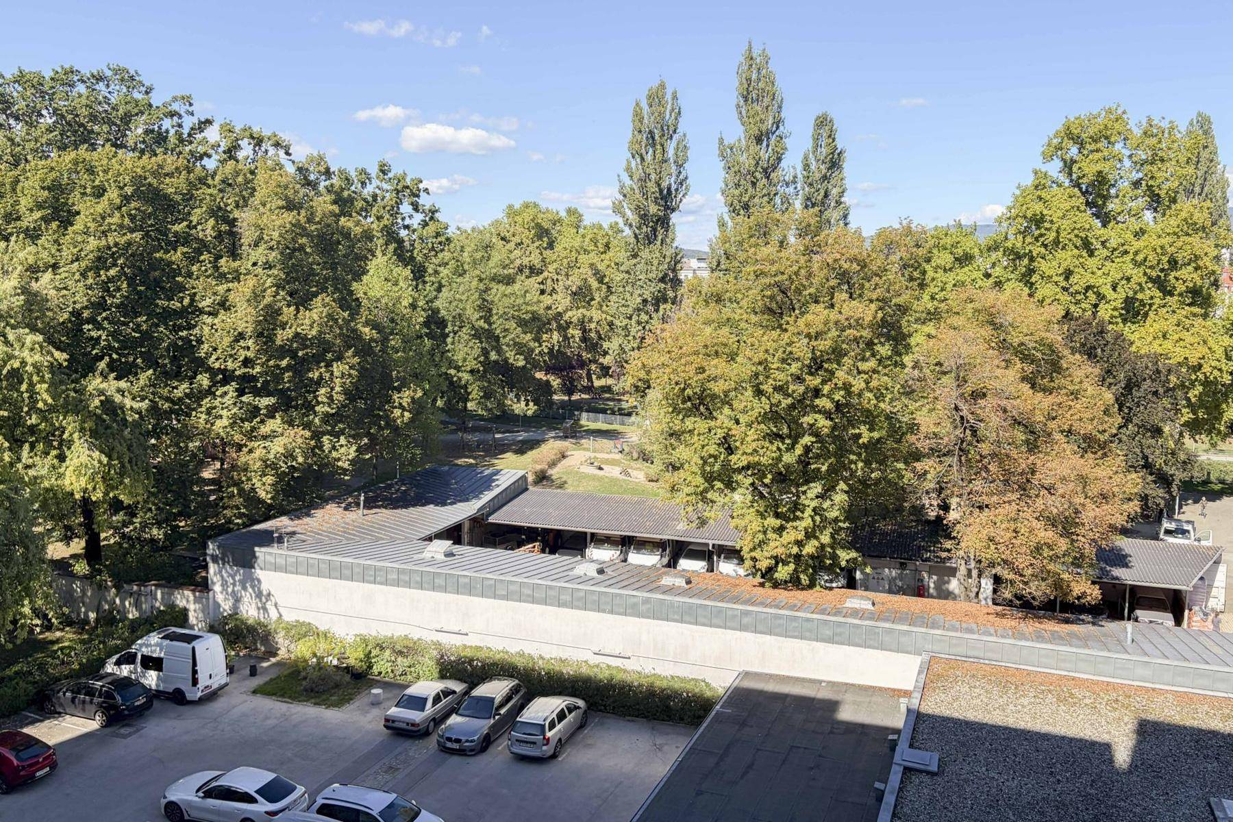 Panoramablick auf eine grüne Umgebung mit Bäumen, Parkplätzen und Gebäuden.