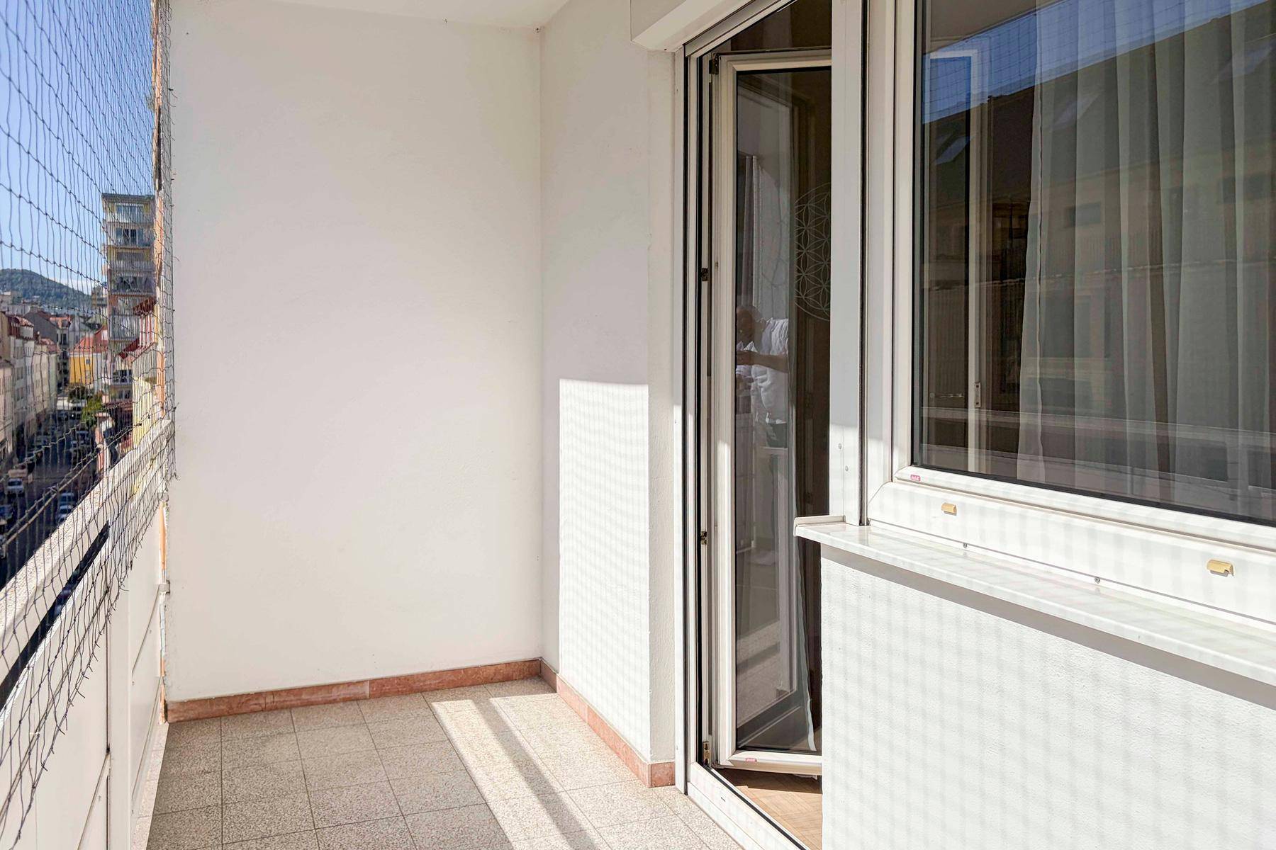 Heller Balkon mit Fliesenboden und Schutznetz, ideal für entspannte Stunden.