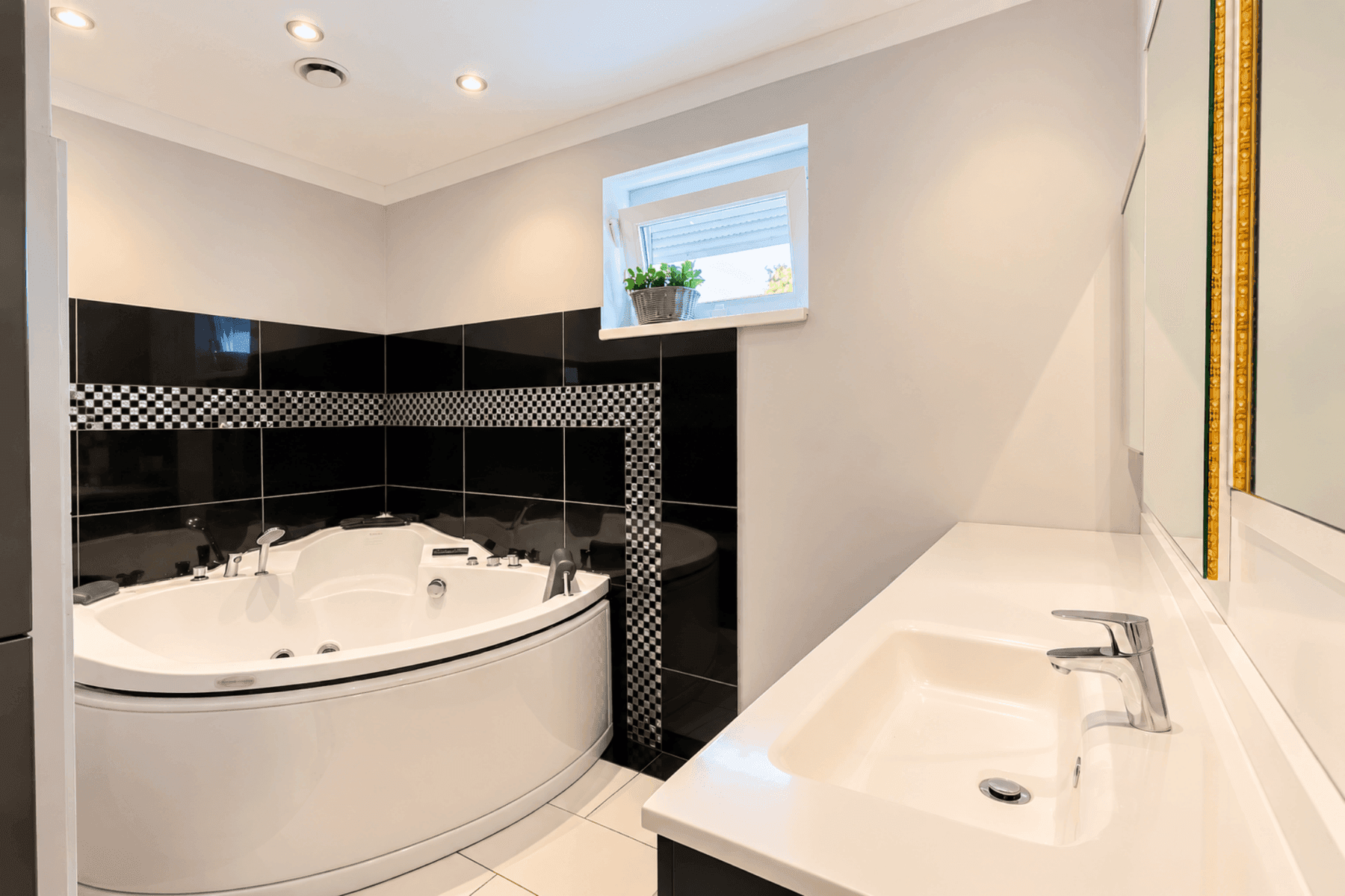Modernes Badezimmer mit Eck-Whirlpool, Einzelwaschbecken und eleganten Schwarz-Weiß-Fliesen.