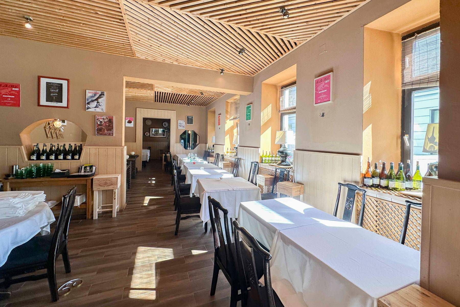 Langer Blick in den Restaurant-Speisesaal mit vielen gedeckten Tischen, Holzboden und einer charakteristischen Holzlamellendecke.